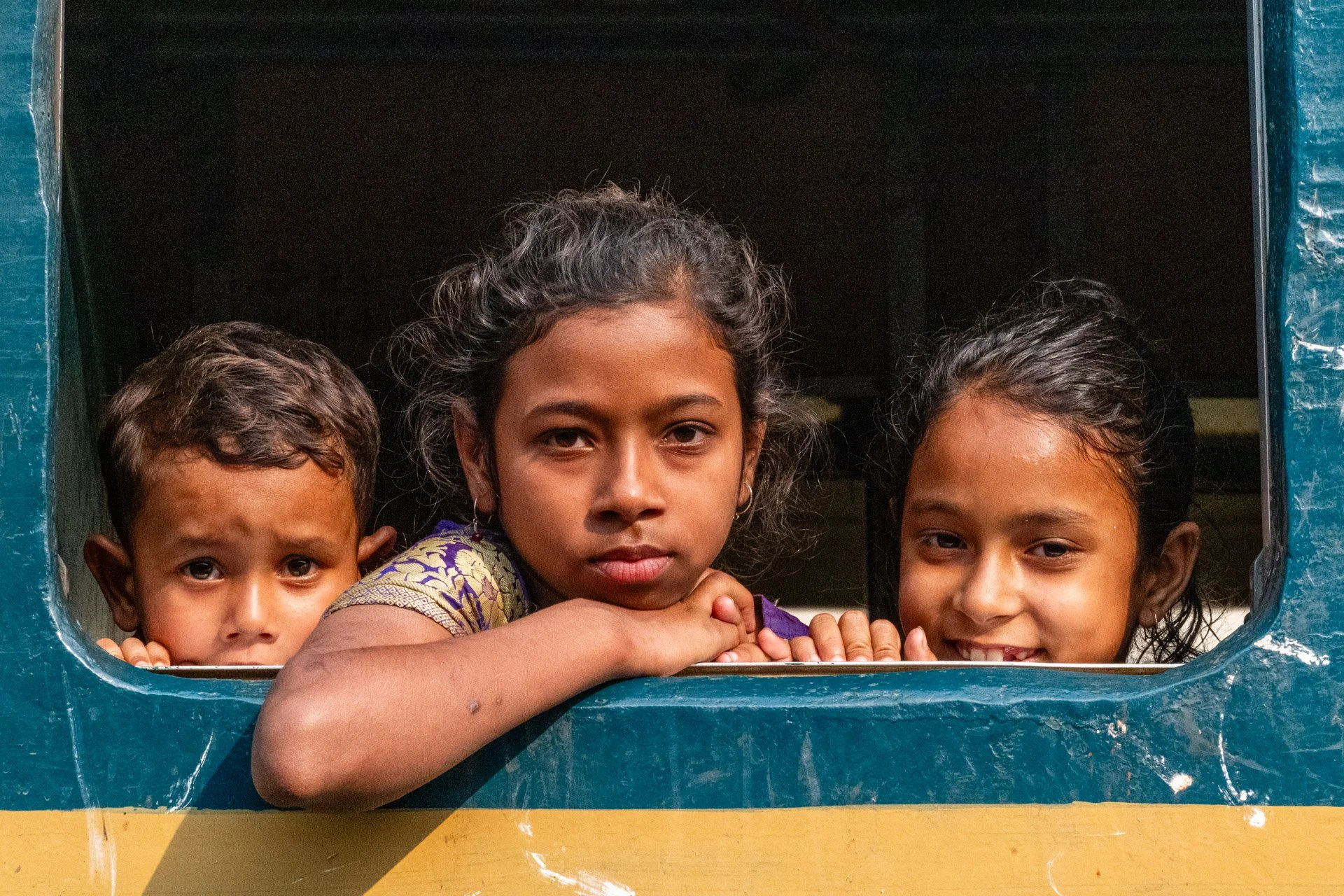 Three children on a train in the station in Bangladesh. 