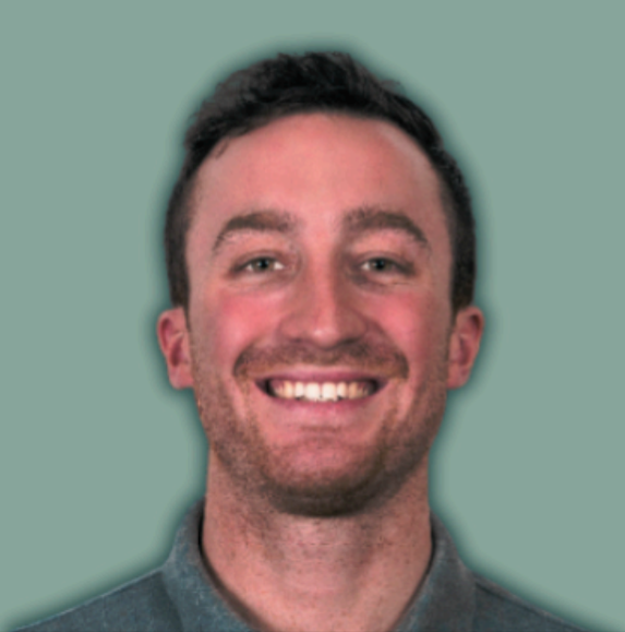 A smiling young man with short dark hair and a light beard, wearing a gray collared shirt, against a plain green background.