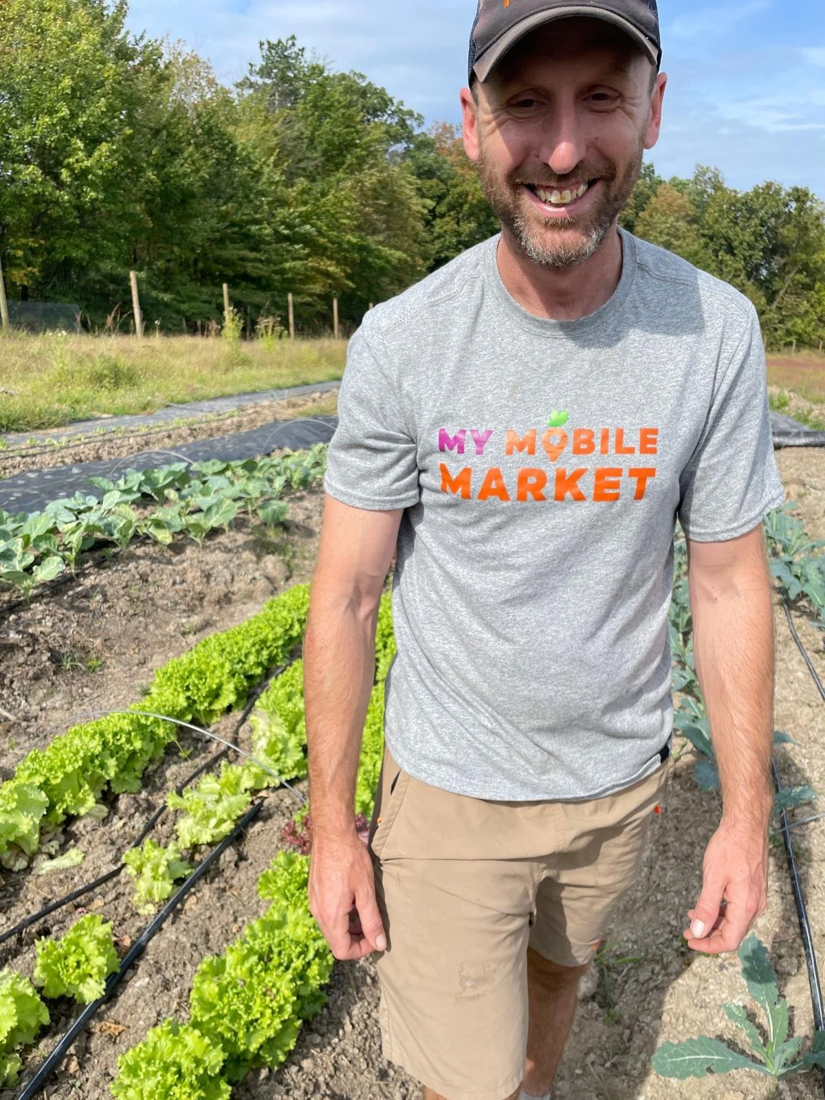 farmer walking in field with lettuce behind