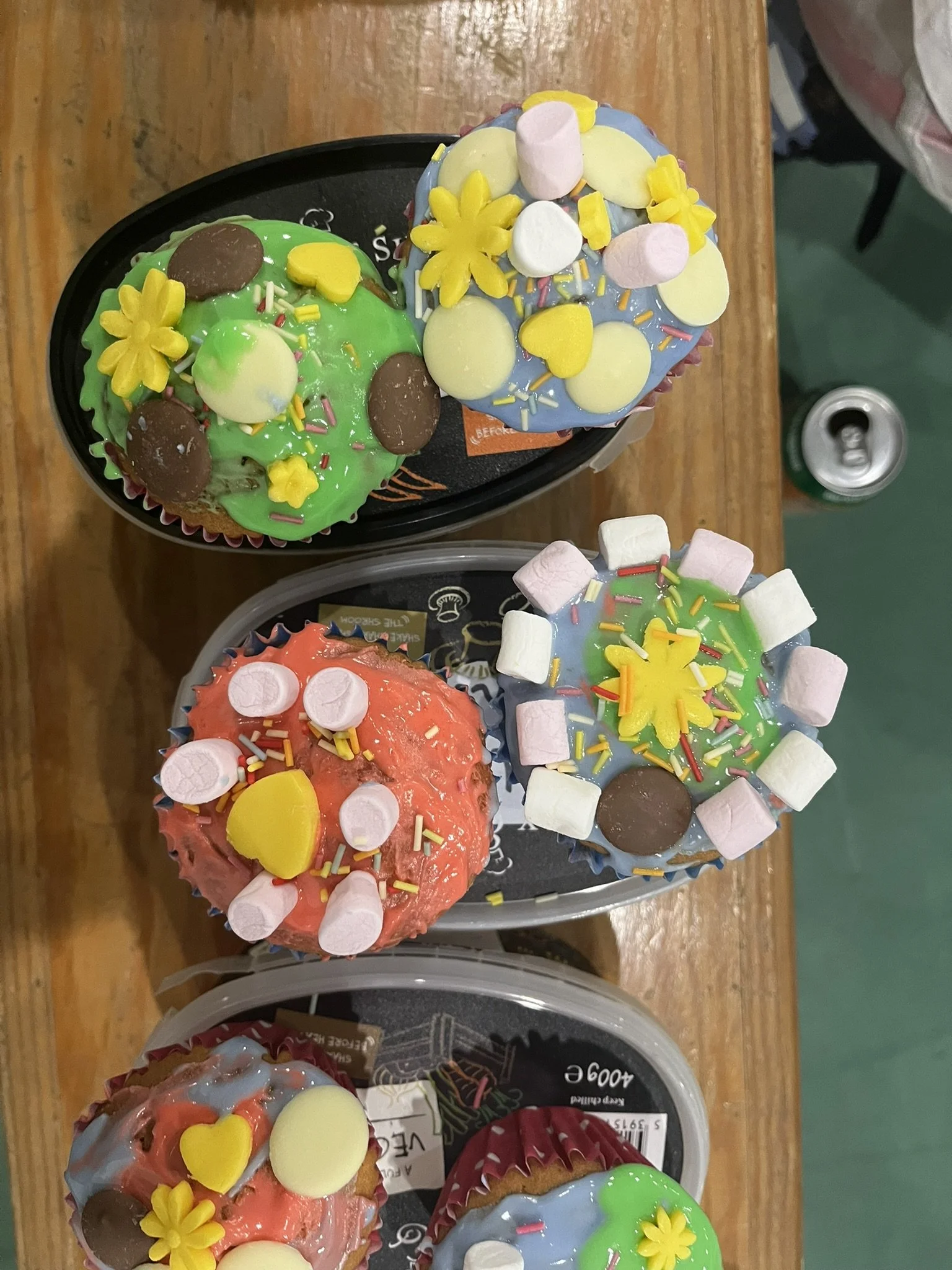 Colorful cupcakes decorated with pastel marshmallows, yellow flowers, chocolate candies, and rainbow sprinkles.