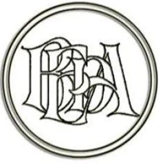 A circular logo with intricate Gothic-style lettering inside.