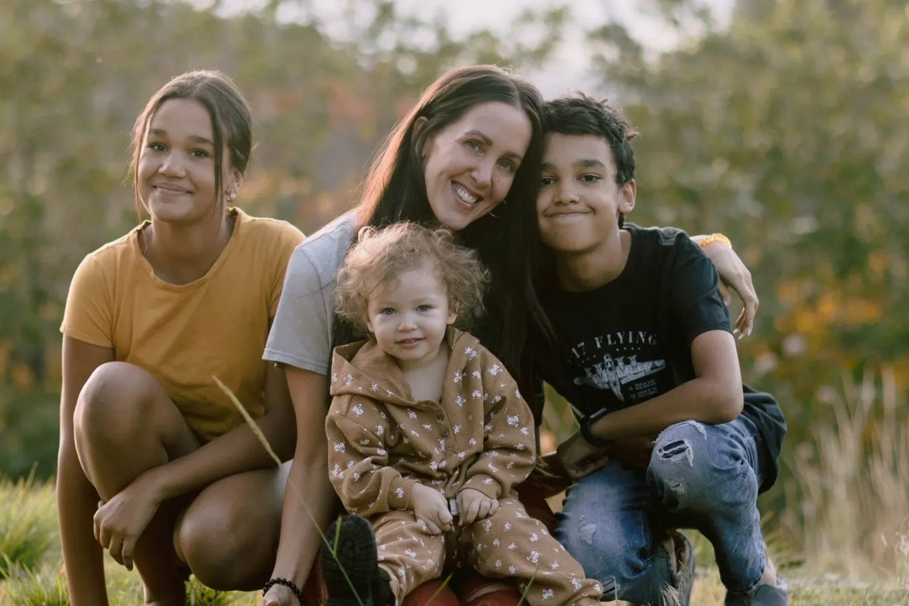 Person in a dark dress holding a camera, standing against a white background.
