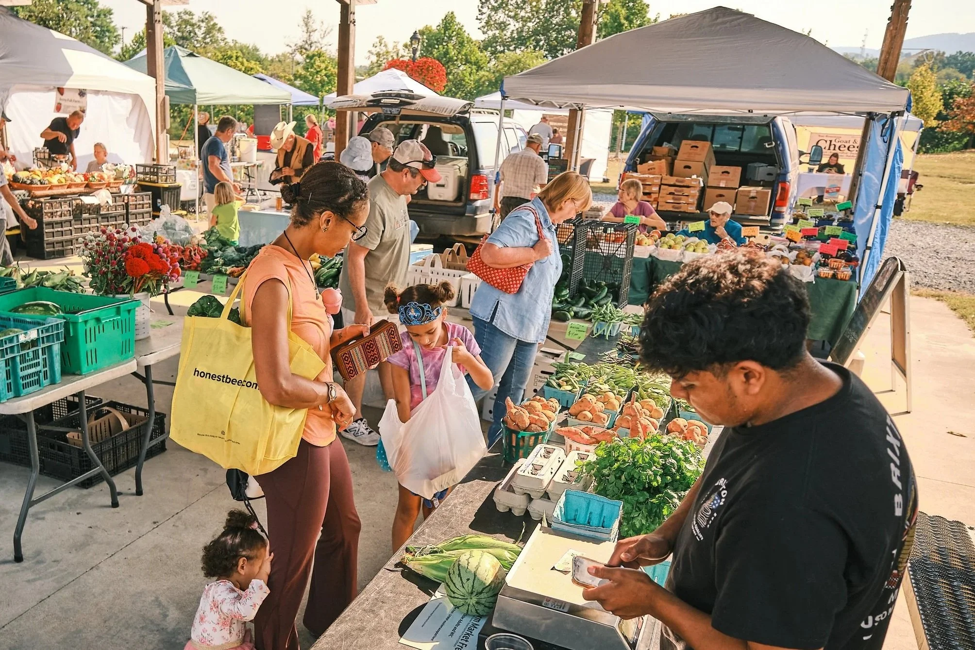 Family buying food from farmer at a farmers market.
