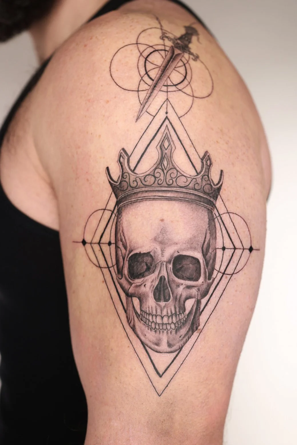 skull with a crown and a sword hanging over with geometric design