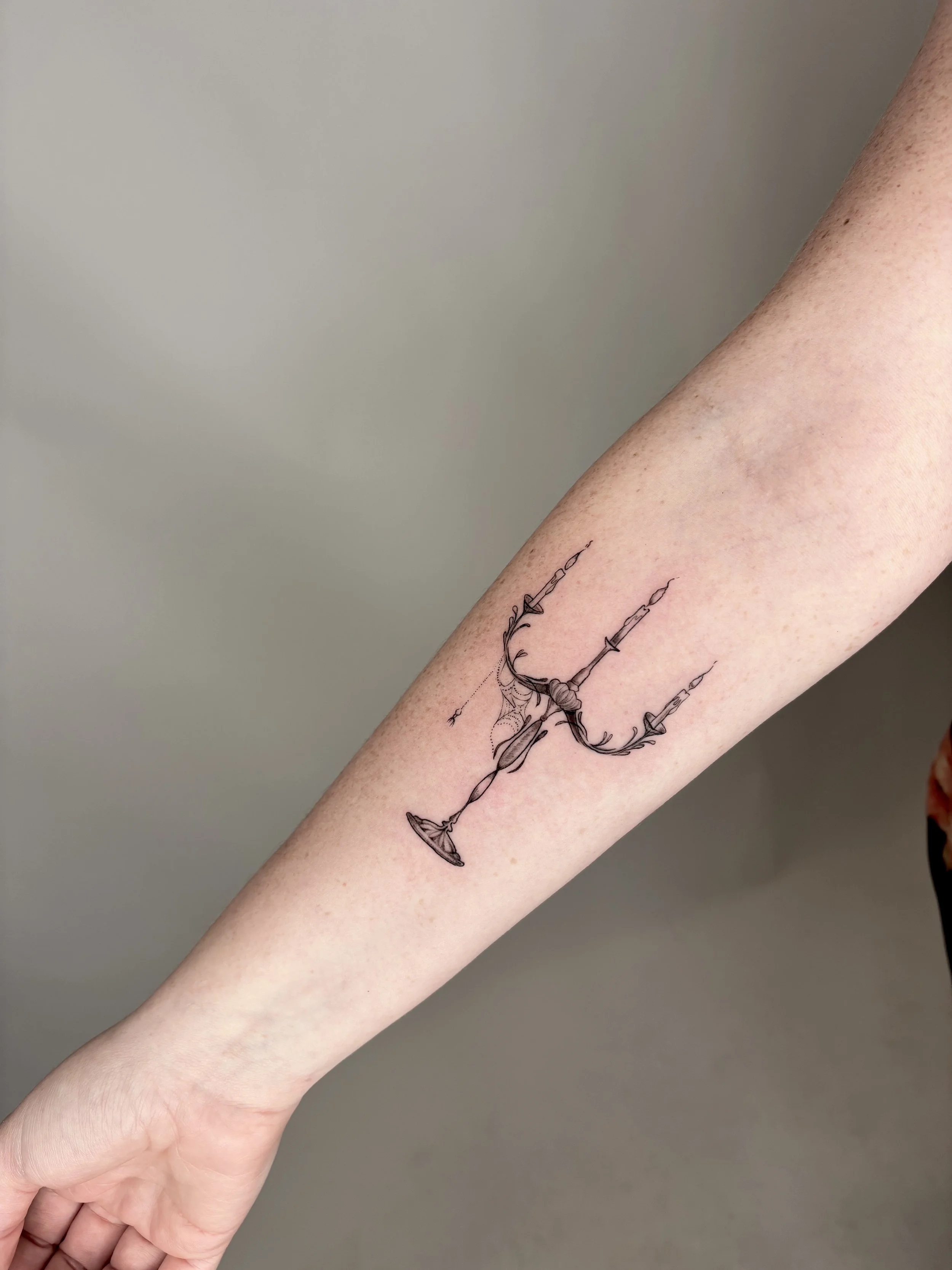 Tattoo of a candelabra with a small spider and web.