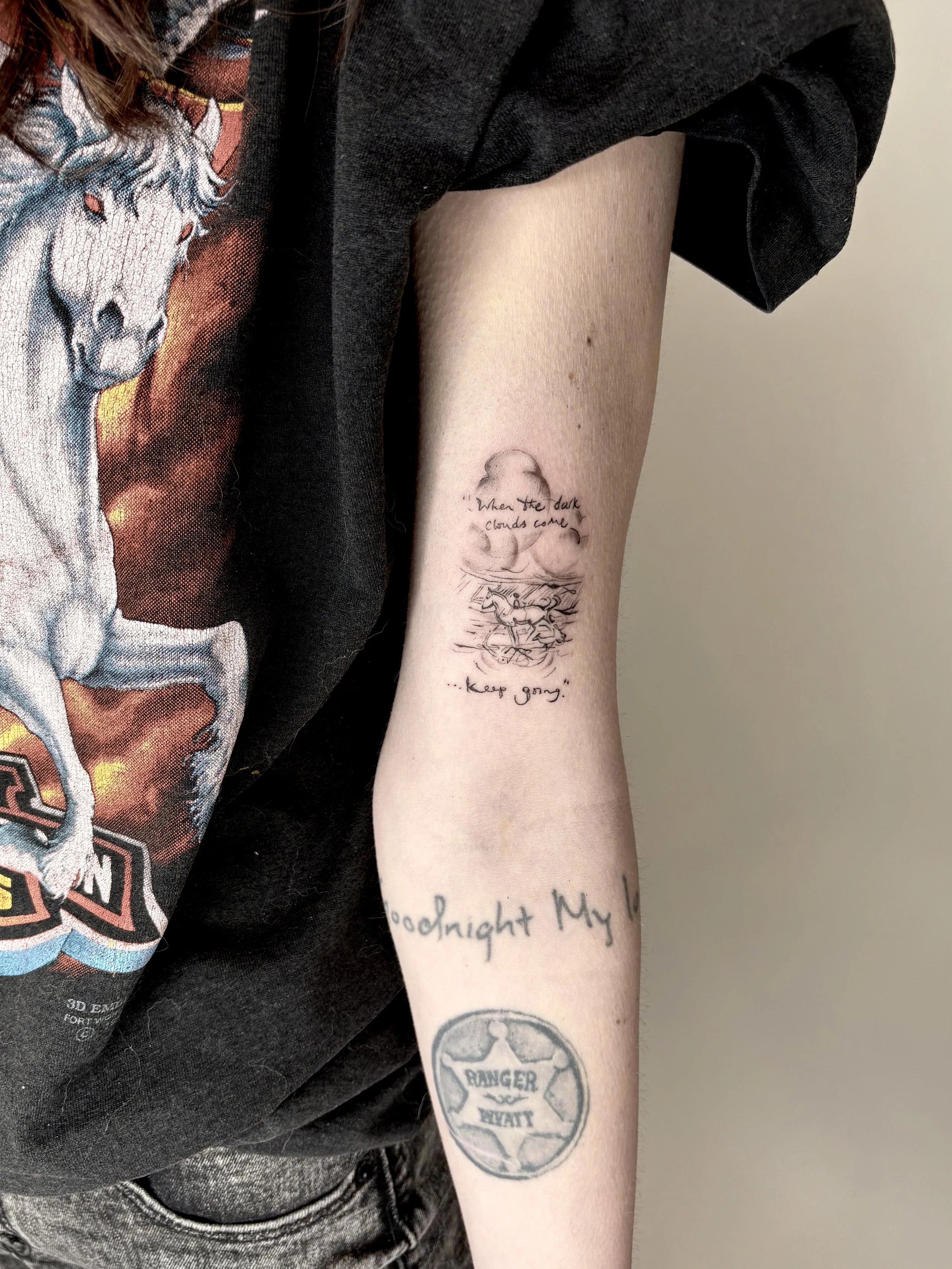 Arm tattoo of an illustration from a book of a horse running through a storm.