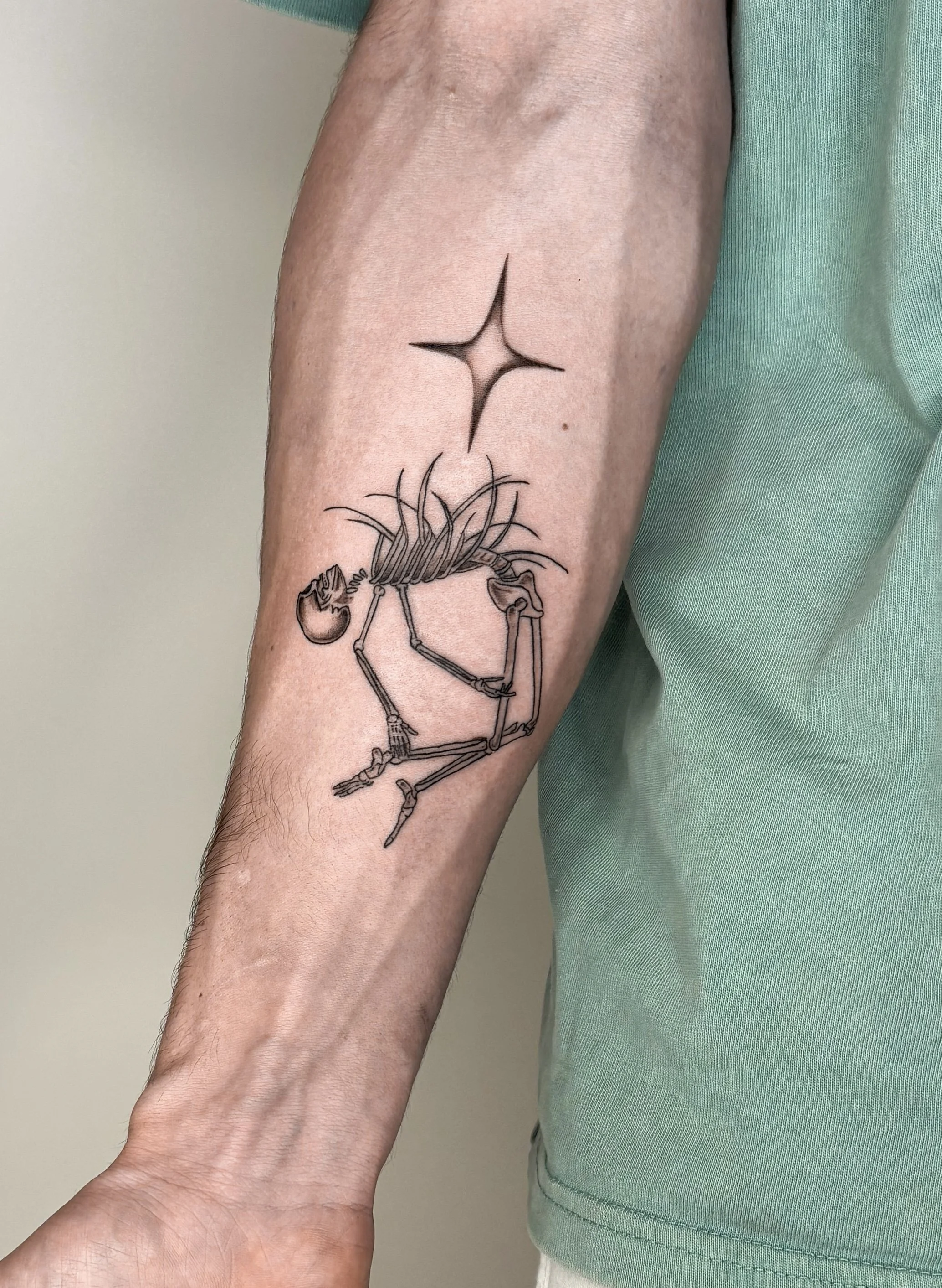 Forearm tattoo of a skeleton figure with a star coming out of the rib cage.