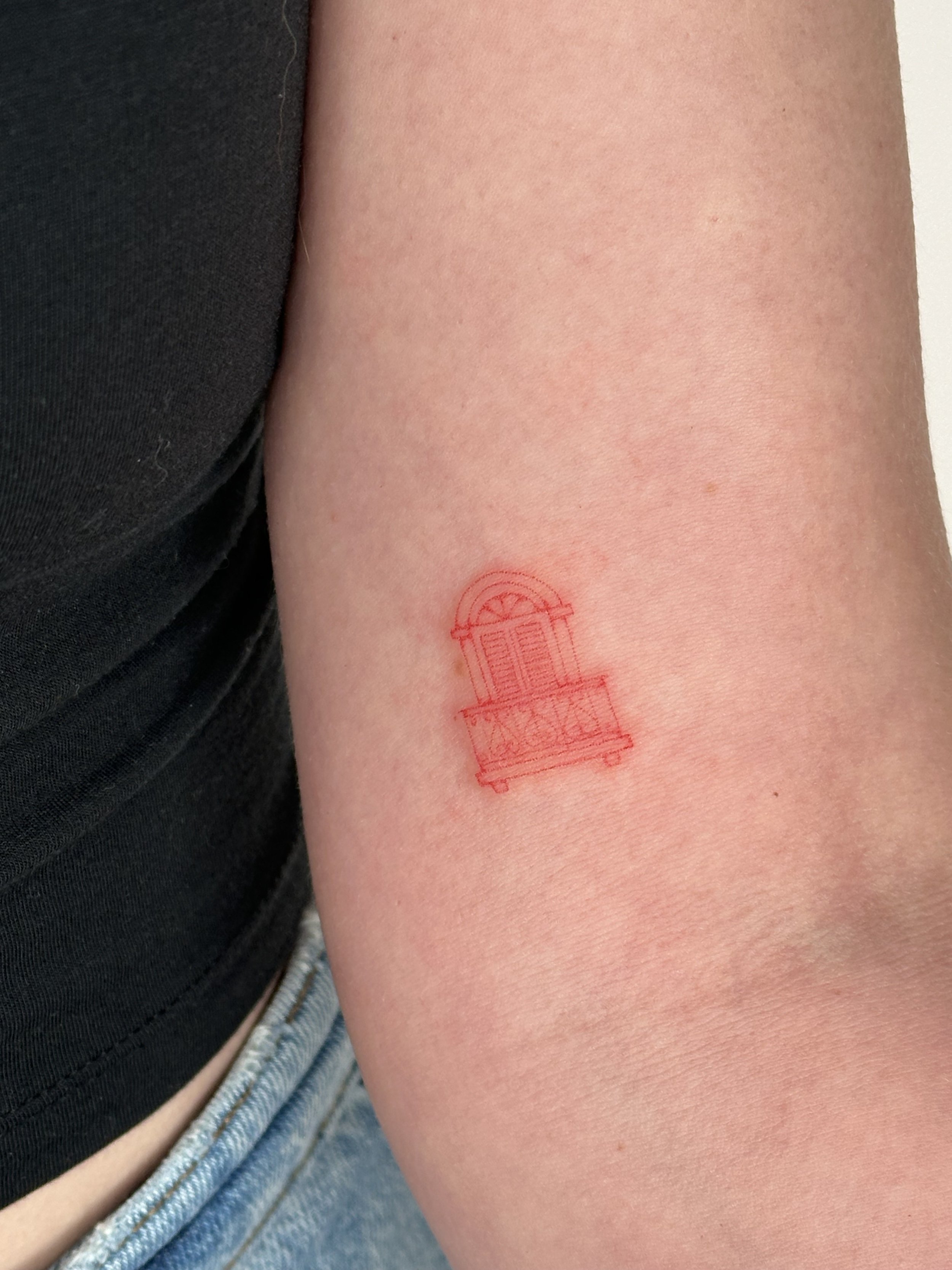 Minimalist red line tattoo of a window with a balcony on arm