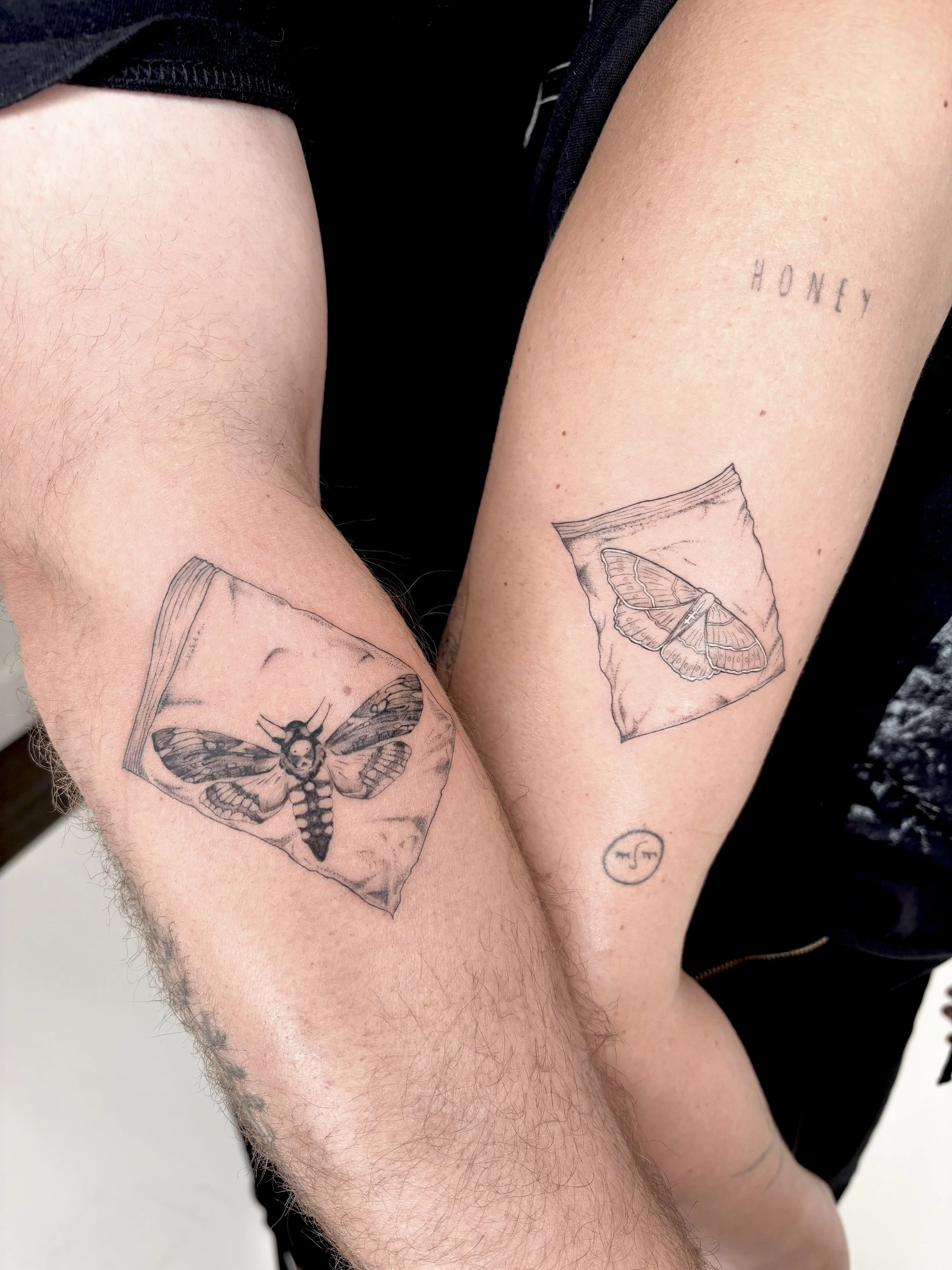 Two people with coordinating moth in ziploc bags on their arms.