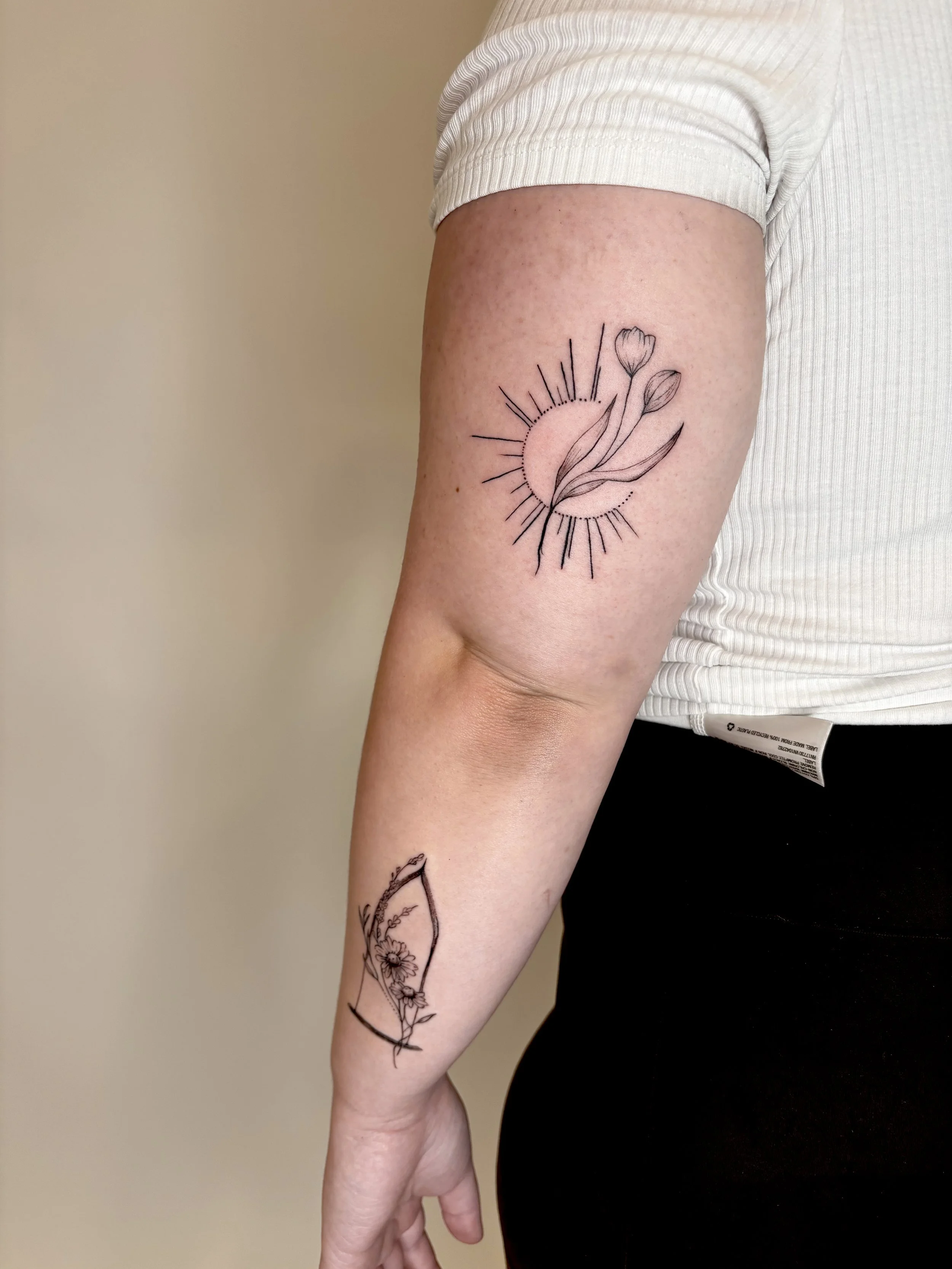 Tattoo of a sun shape with tulip flowers.