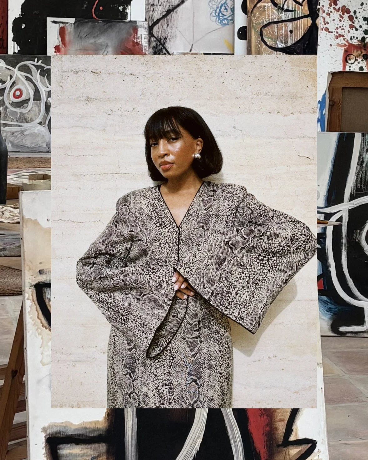 Person in snake-print outfit posing with folded arms, surrounded by abstract artwork.