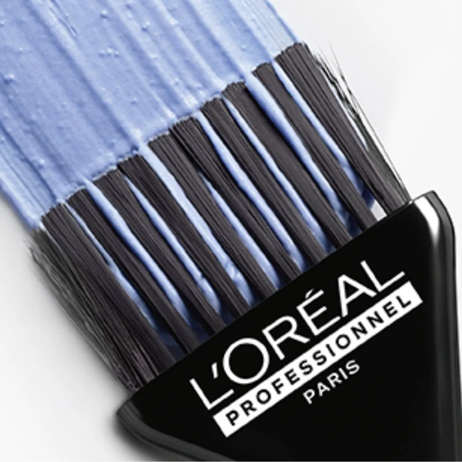 Close-up of a pile of loose mascara wands with a L'Oréal Professionnel Paris label in the foreground.