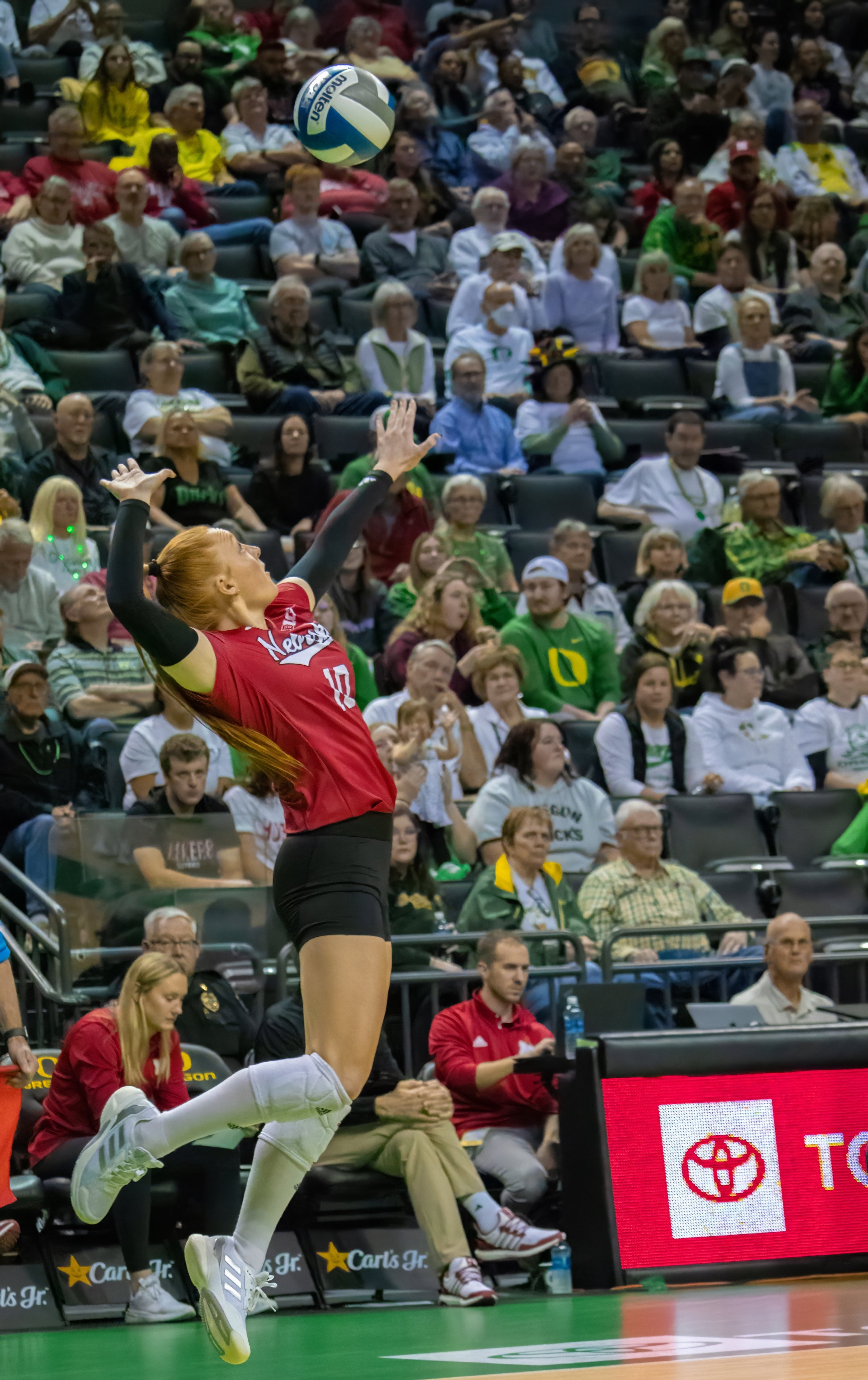 University of Nebraska defensive specialist Olivia Mauch, #10, begins rally from jump serve. Photo by Emily Manciu