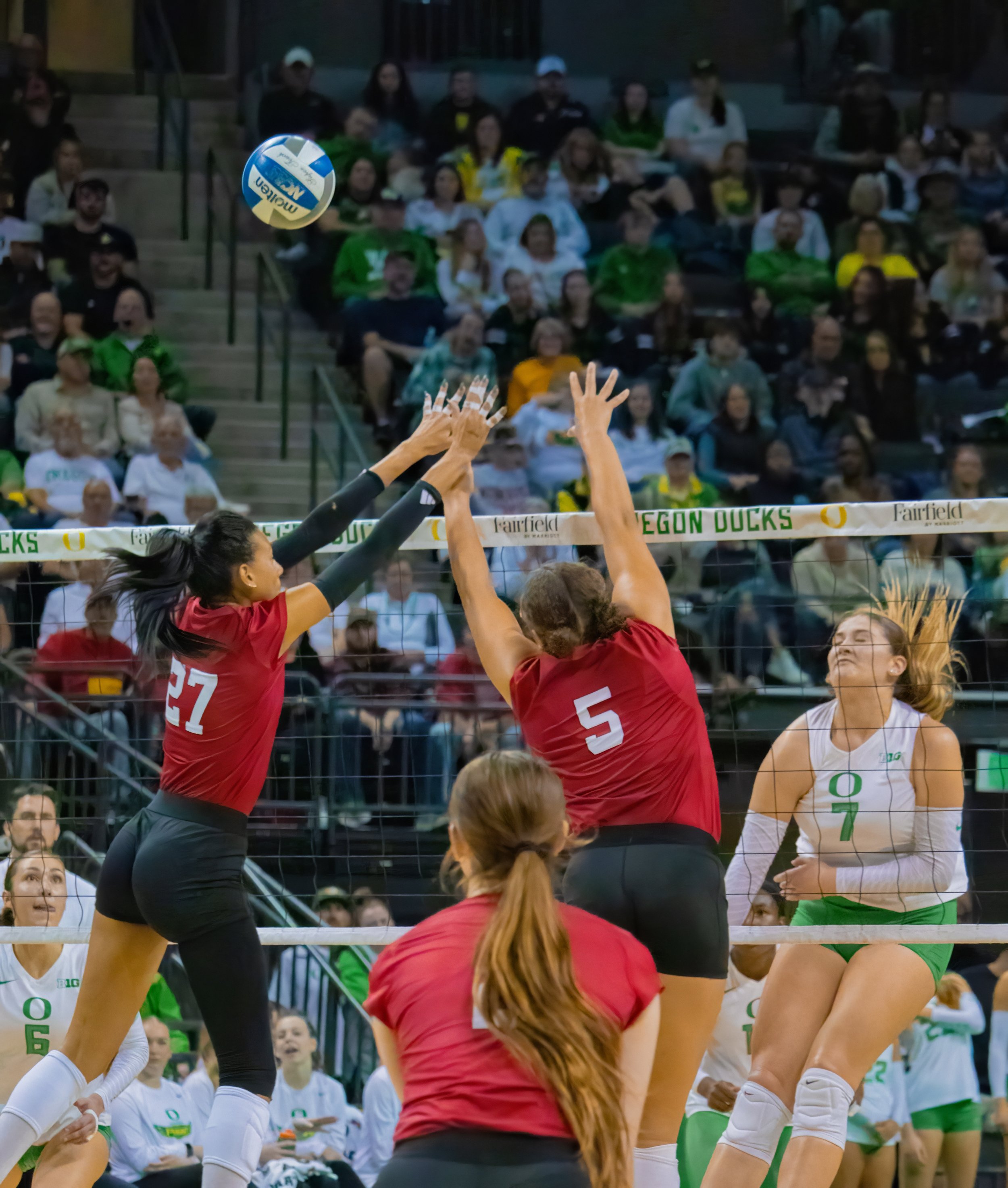 University of Oregon duck middle blocker Colby Neal, #7, spikes past two University of Nebraska cornhusker players, Rebekah Allick, #5, Middle Blocker, and Harper Murray, #27, outside hitter. Photo by Emily Manciu