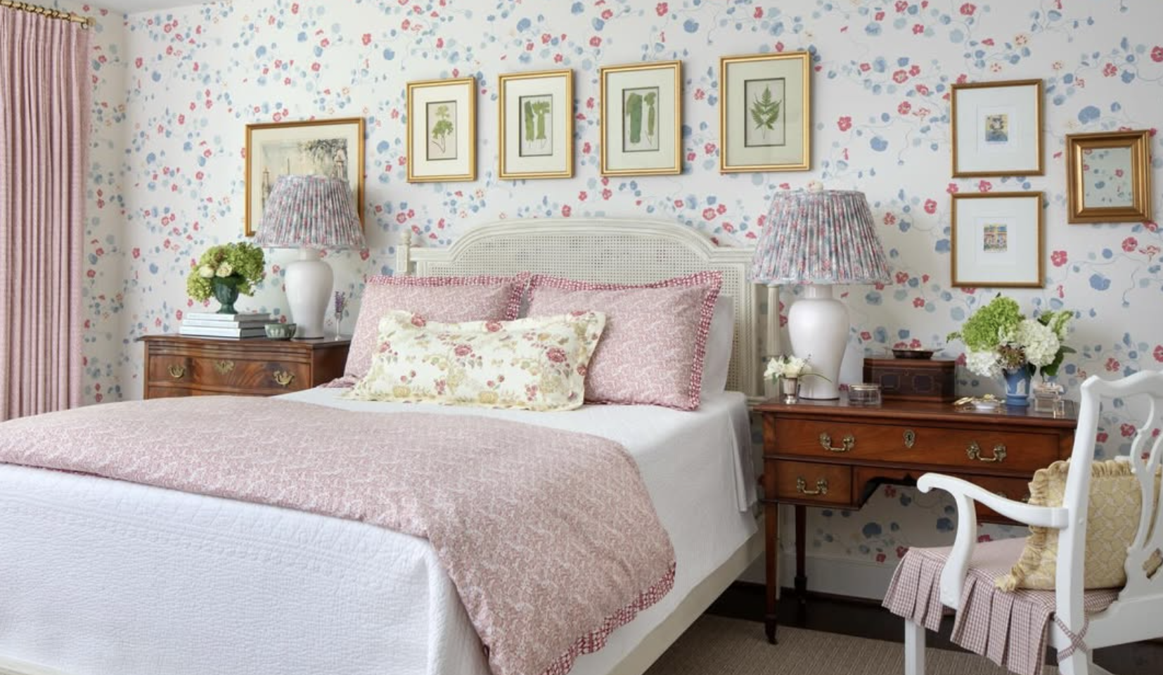 A cozy bedroom with a white bed, pink patterned bedding, and floral pillows designed by Richmond, VA interior designer Jenny Holladay Design.