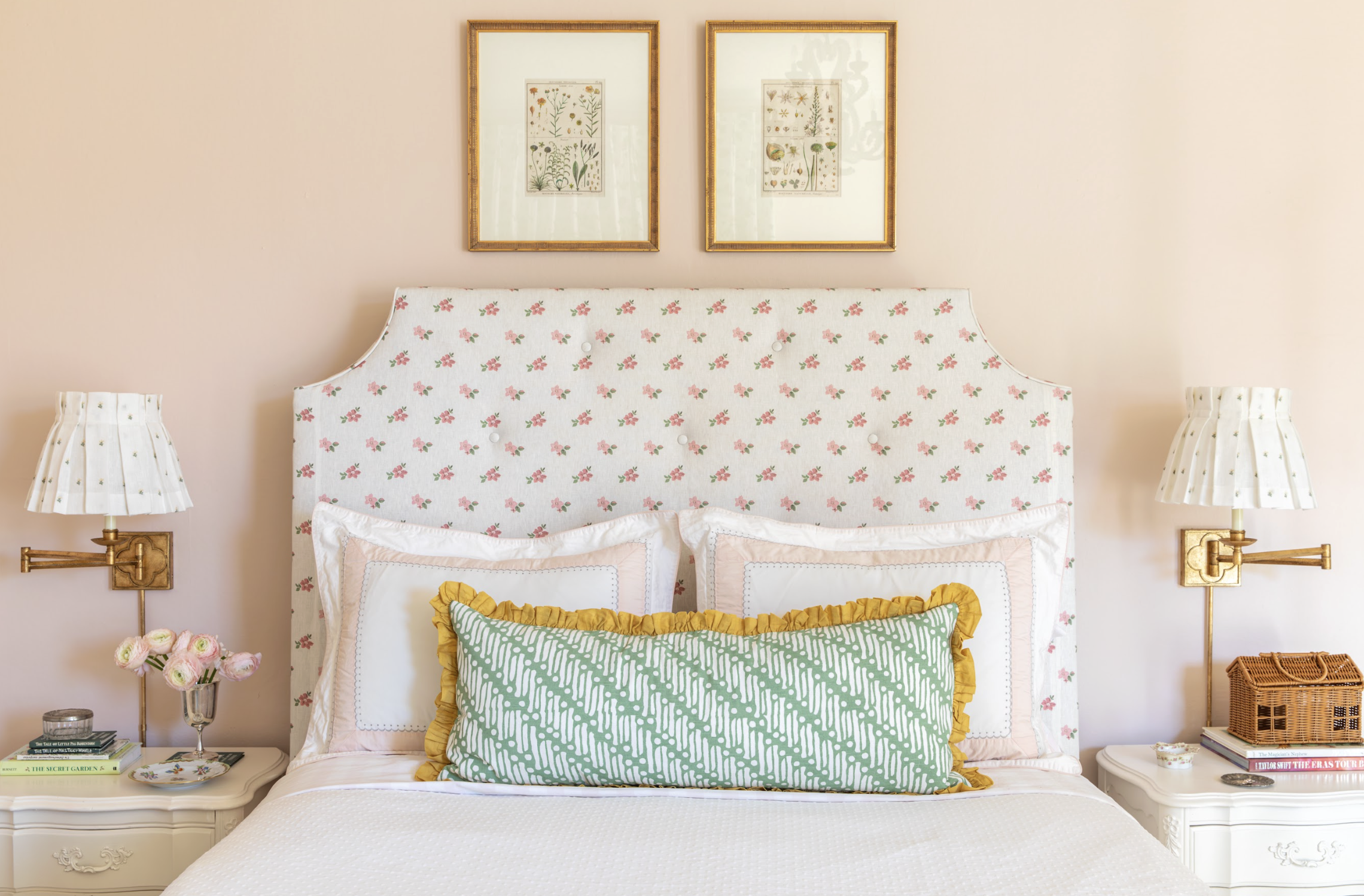 A cozy bedroom with a floral upholstered headboard, two white pillows with pink trim, and a decorative green pillow with yellow ruffle designed RIchmond, VA interior designer Jenny Holladay Design.