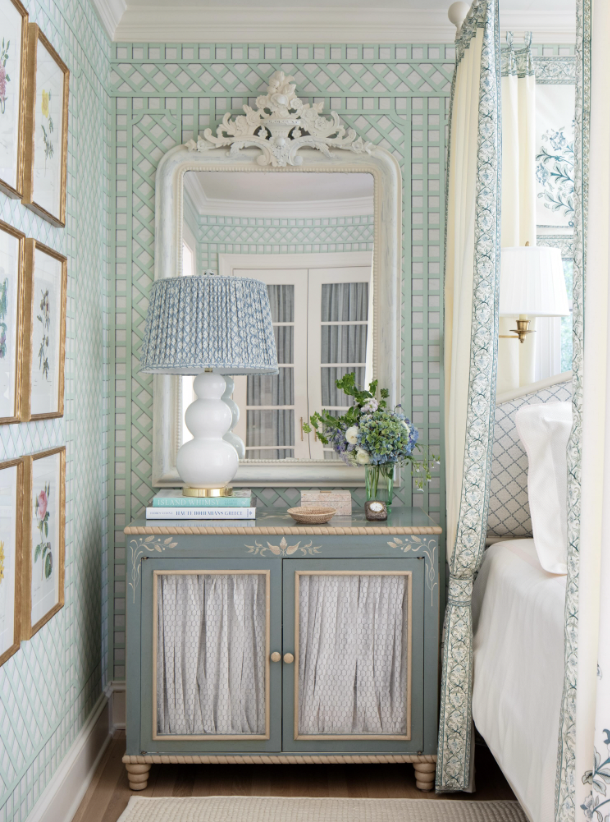 A bedroom corner with a vintage blue dresser, a large white-framed mirror, a blue and white table lamp, and a vase of flowers on the dresser created by interior designer Jenny Holladay Design who's based in Richmond, VA.