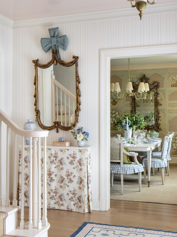 An elegant dining room with a chandelier, floral wallpaper, and a round table set with fine china and floral centerpieces created by Jenny Holladay Design in Richmond, VA.