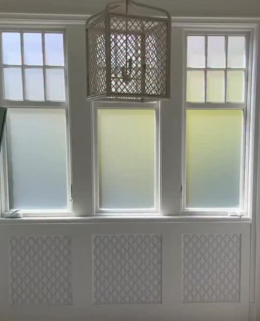 A window with three sections and a hanging light fixture with a lattice pattern.