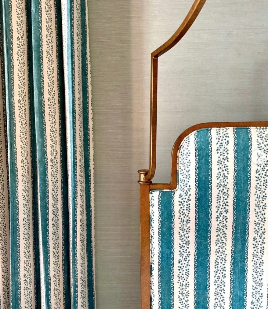 Close-up of a staircase with blue and white striped patterned upholstery, next to matching curtains with a similar pattern.