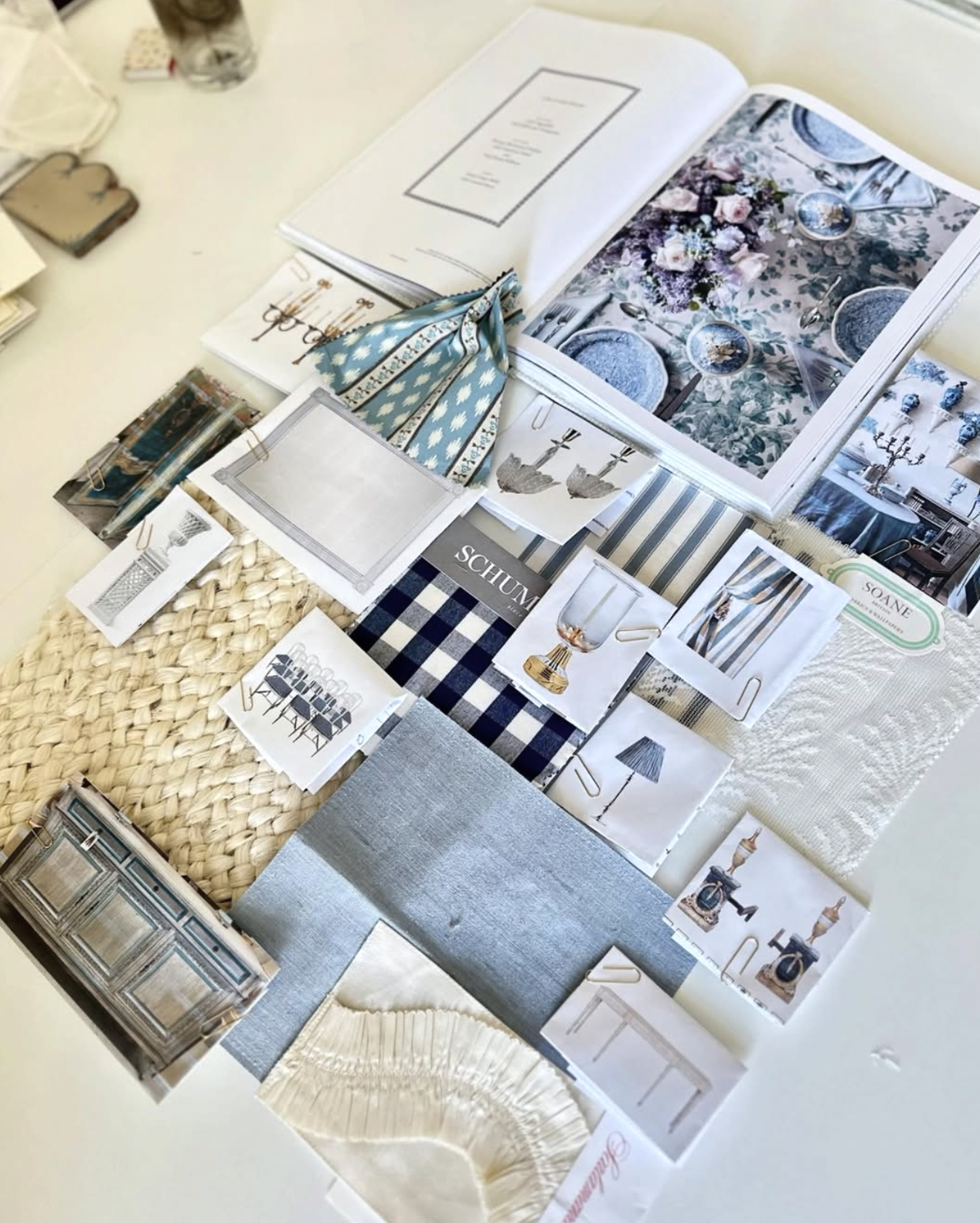 A table displaying fabric swatches, photos, and samples for interior design or decorating ideas.
