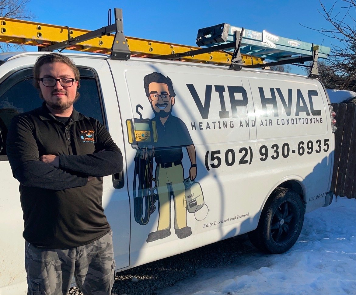 A man with glasses and a beard standing with arms crossed beside a white work van. The van has the logo and contact info for VIP HVAC Heating and Air Conditioning, with a cartoon image of a technician holding tools. The van is parked outdoors on snow with a ladder on top.