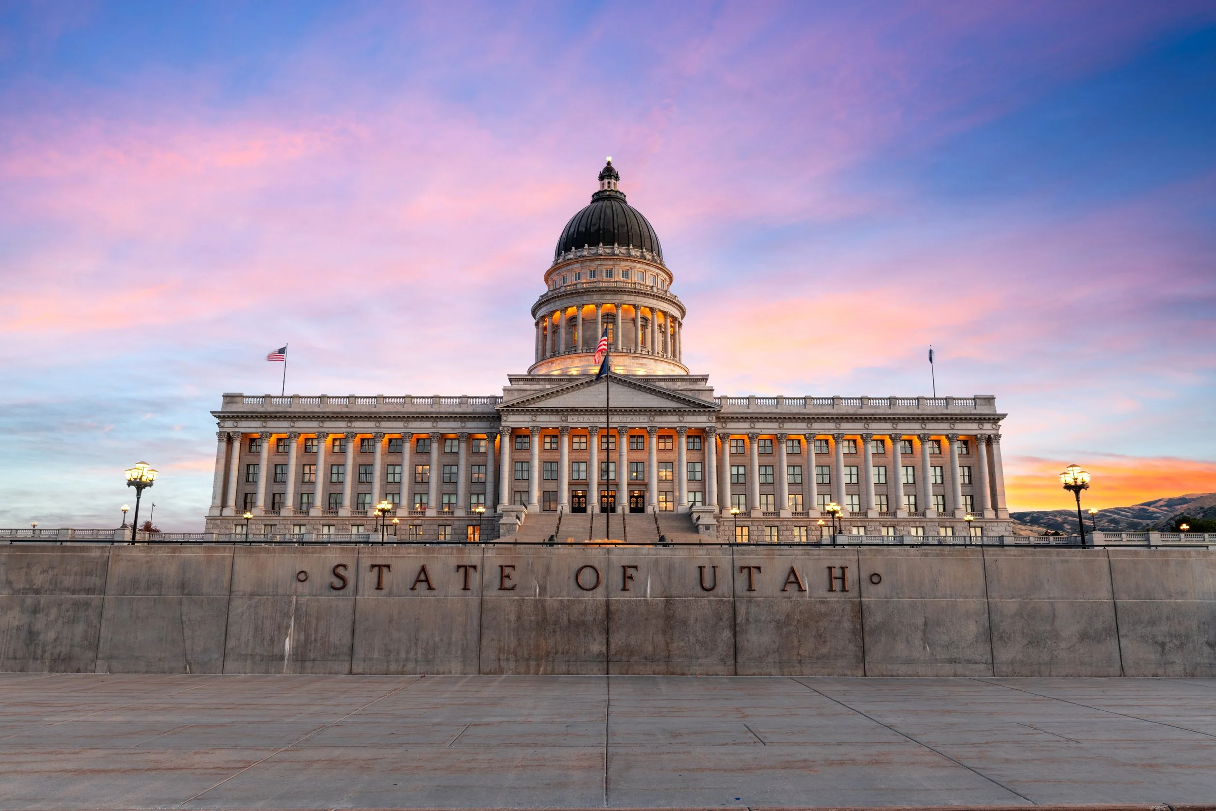 The Utah State Capitol building at sunset with a colorful sky.