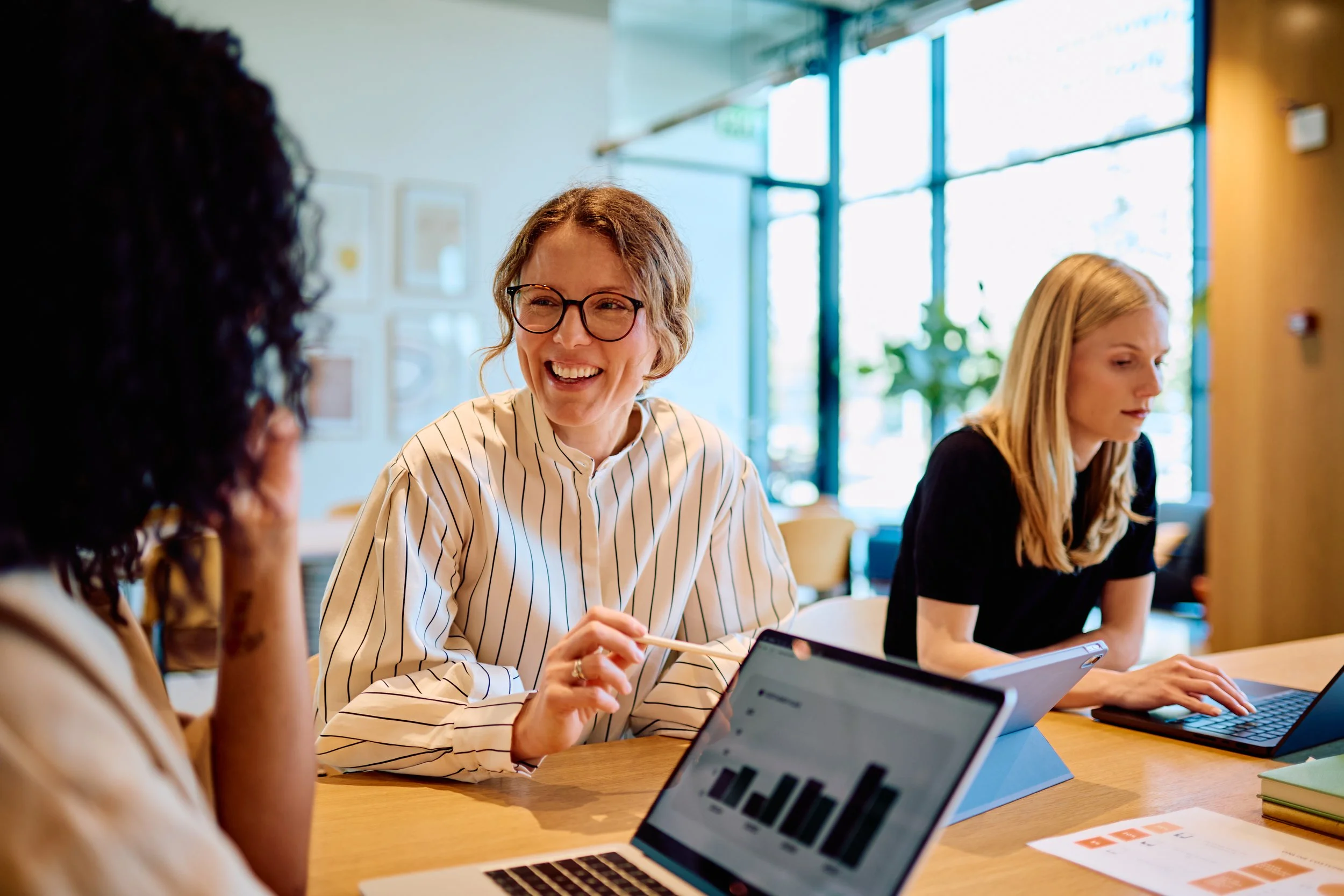 A group of women sitting at a table in a bright, modern office.