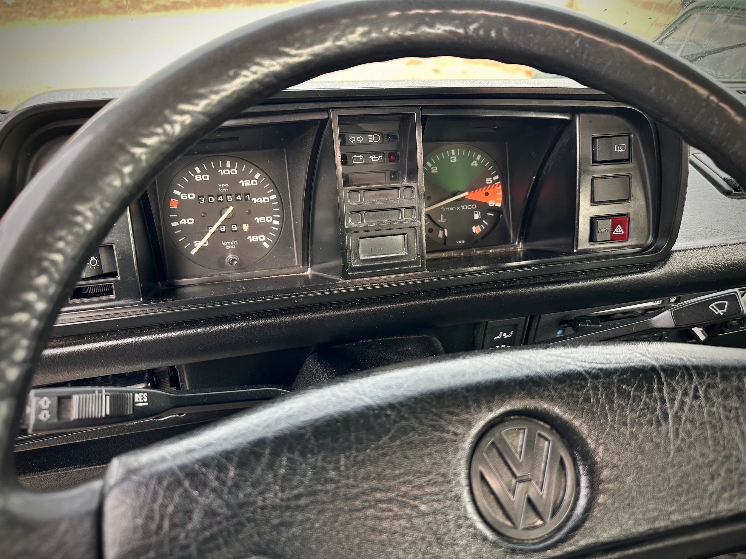 Dashboard of a vintage Volkswagen Vanagon camper van showing a speedometer, tachometer, and various warning lights.