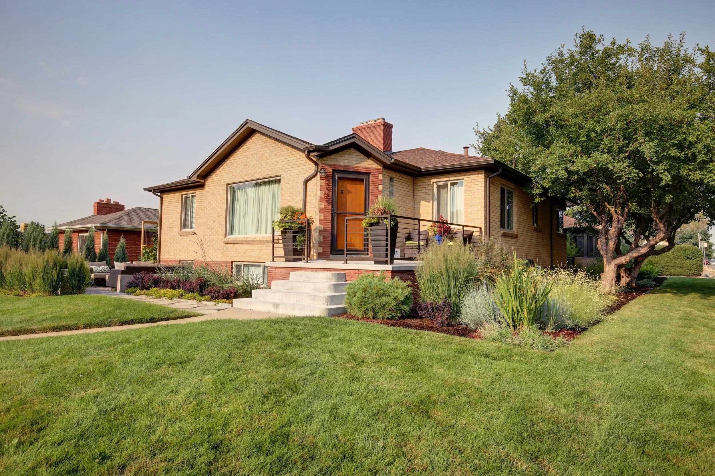 Beautiful Denver brick home with manicured lawn and colorful gardens designed by The Green Fuse for curb appeal.