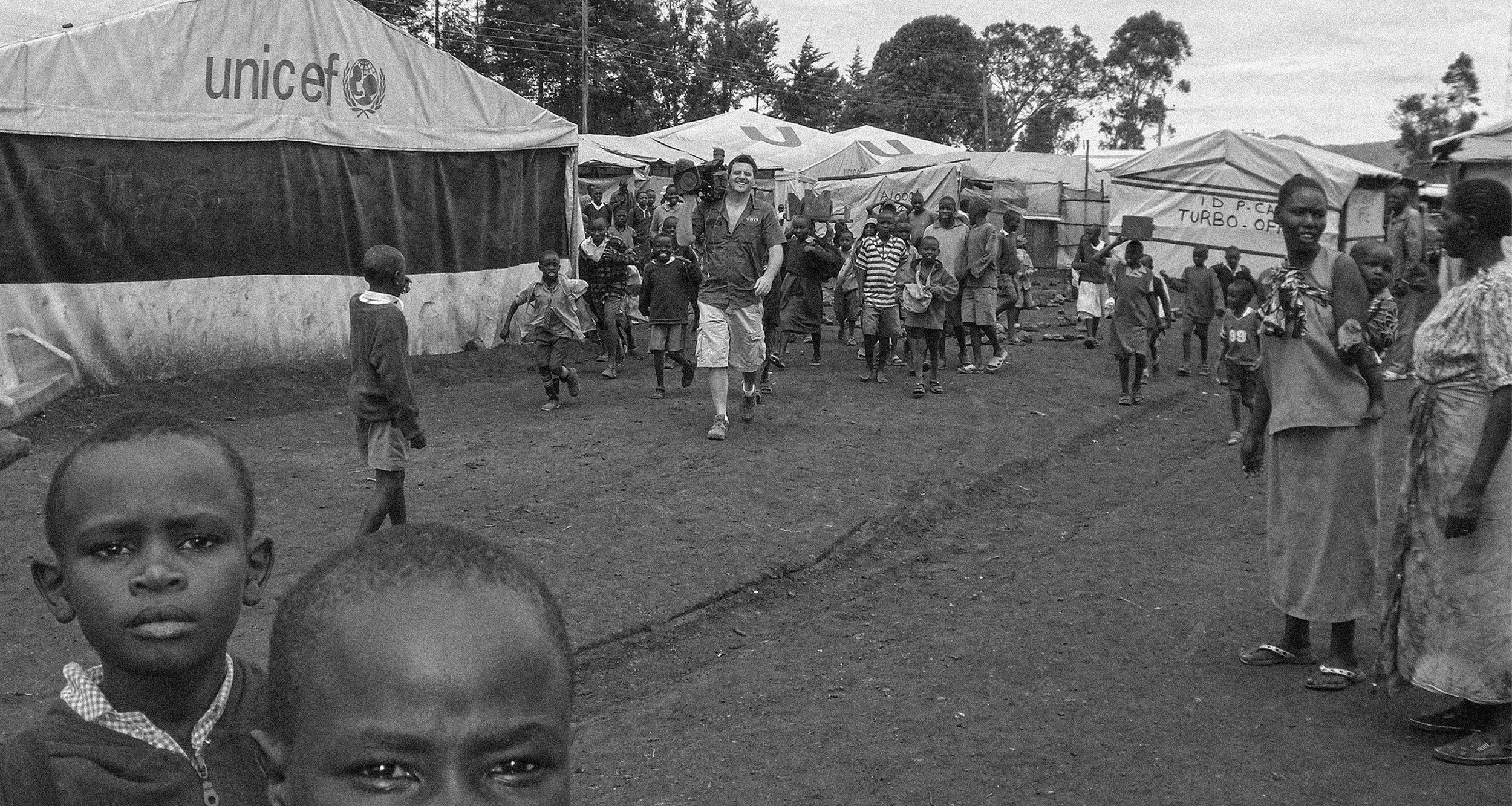 Children and families gathered outside a UNICEF tent in a refugee camp in Kenya's Rift Valley, photographed during a documentary project in 2009