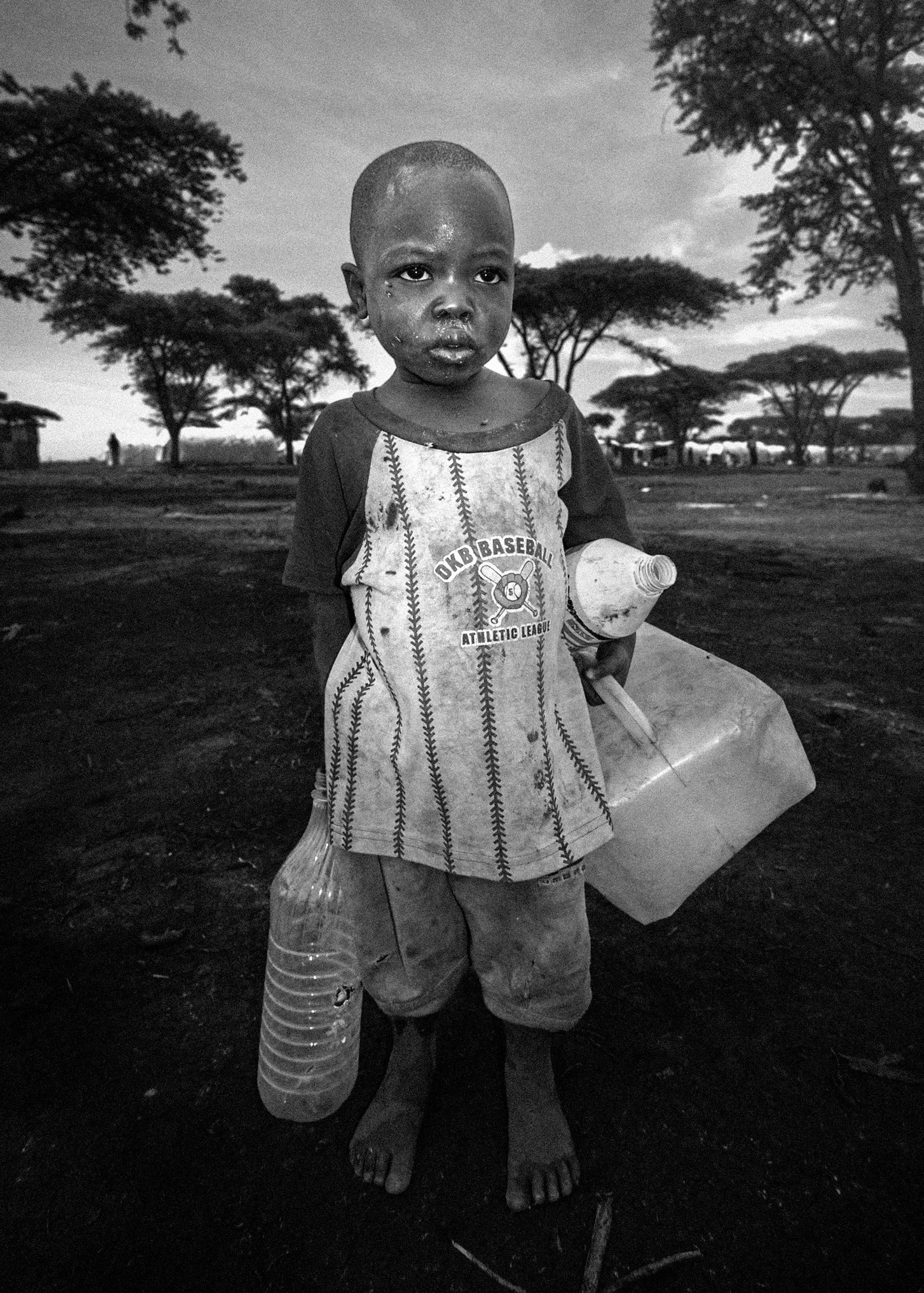 Portrait of a young child carrying water containers in a refugee camp in Kenya's Rift Valley, photographed during documentary filming in 2009