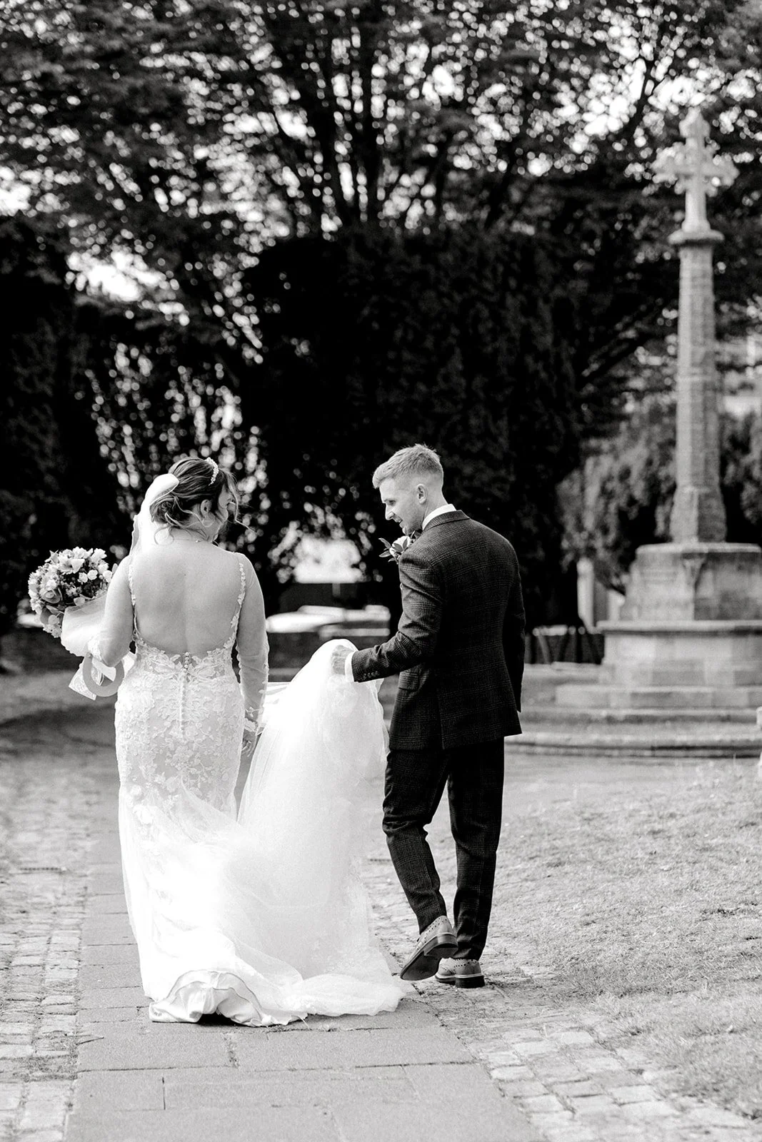 groom helps bride and admires her dress in candid moment on their wedding day photographed by laura jane photography essex wedding