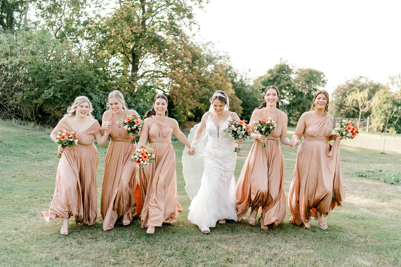 bride and bridesmaids having fun at apton hall running together captured by laura jane photography