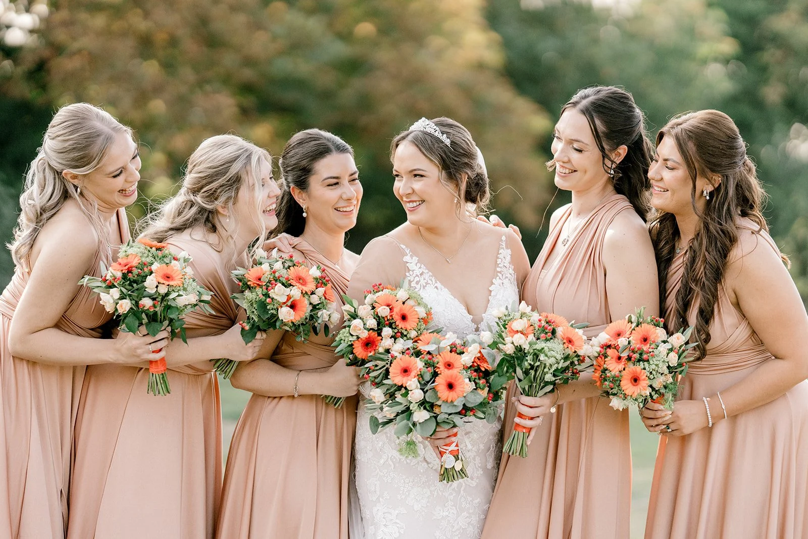 bride and bridal party having a laugh at apton hall in the sun during september wedding