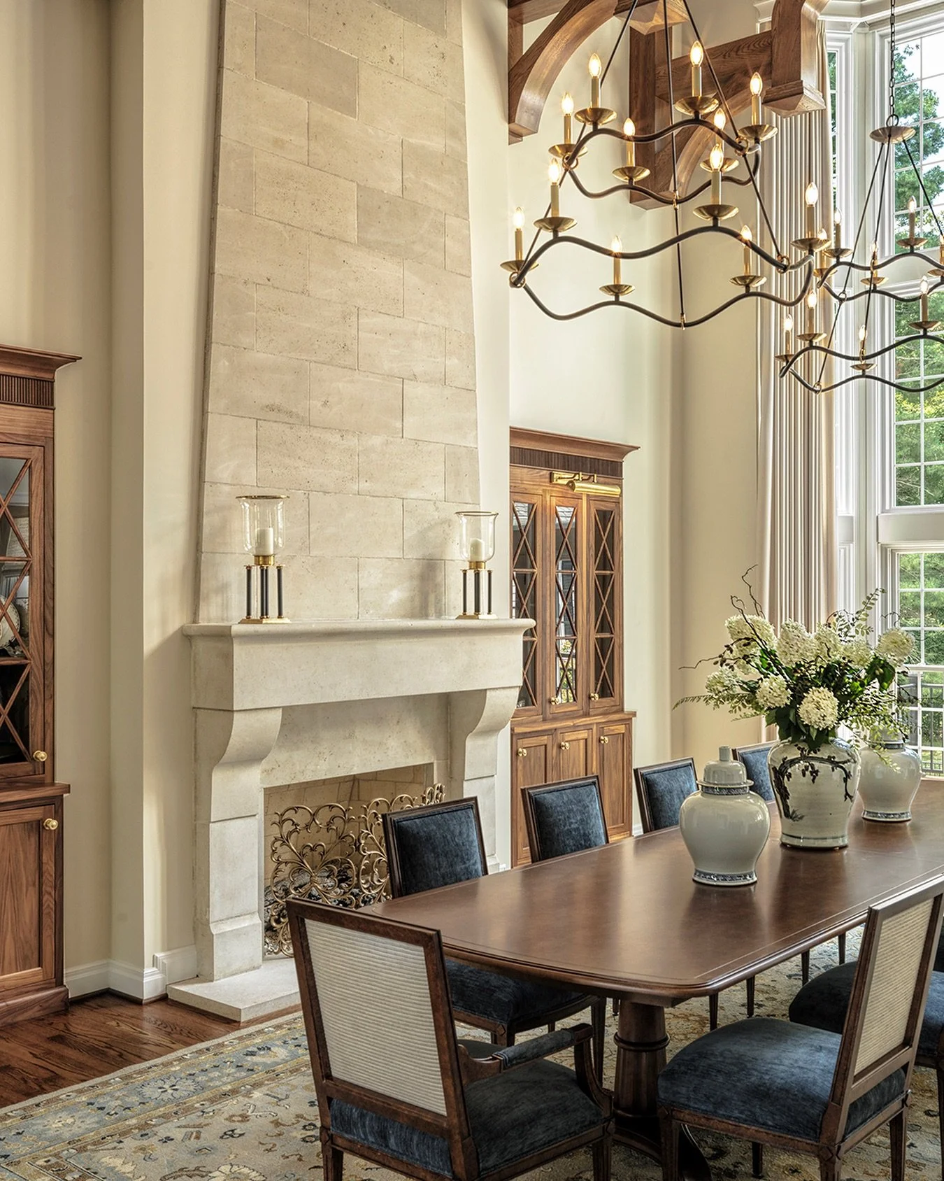 This former living room space was reimagined into a dramatic two story formal dining room. The Birchwood natural stone fireplace surround with complementing wall cladding spans all the way to the ceiling, highlighting the beautiful decorative wood be