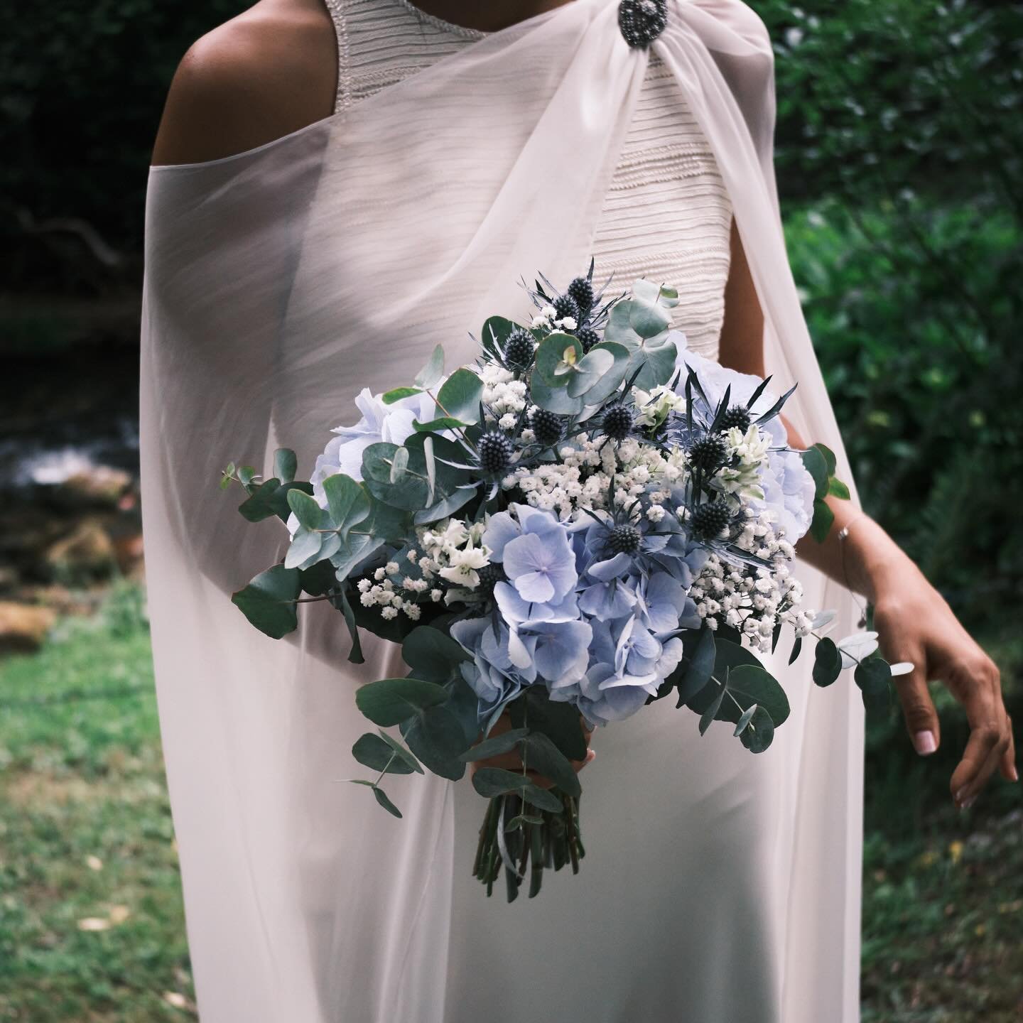 Valentina, la novia que se cas&oacute; en Galicia rodeada de hortensias azules. Llevaba un cuerpo de pedrer&iacute;a bordado con jaretas, falda de sat&eacute;n de seda y capa de muselina cogida por un broche art deco.