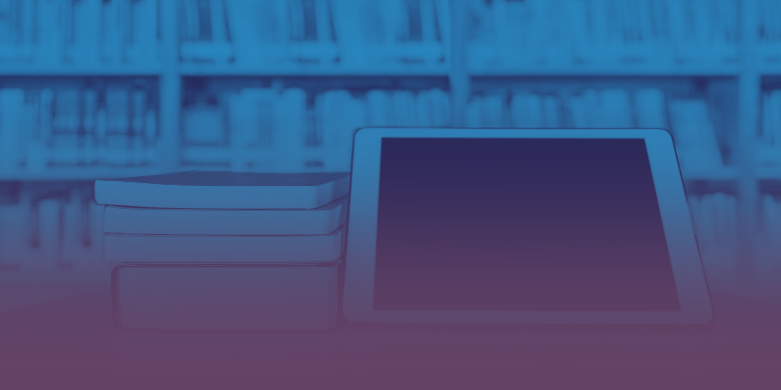 Bookshelves in a library with a table and a laptop on a desk in the foreground