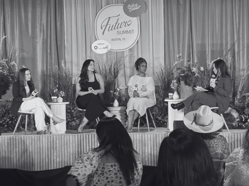 Four women sitting on stage at the Future Summit in Austin, TX, engaging in a panel discussion. The stage is decorated with plants and flowers, and a large sign hanging behind them displays the event name.