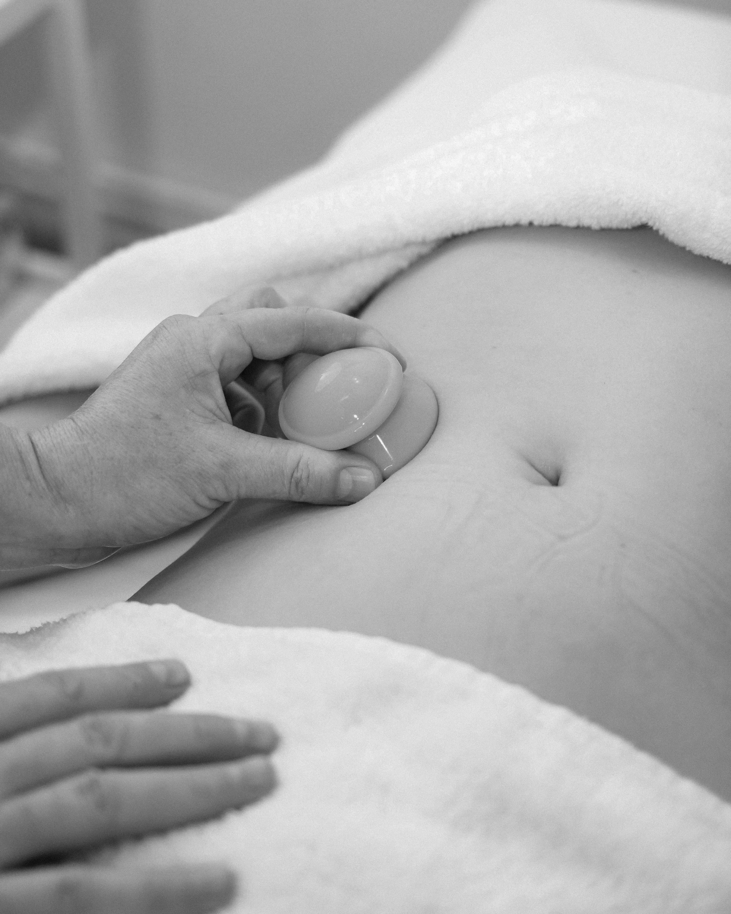 Close-up of a hand holding a small egg, with a partially opened egg shell nearby. In the background, there's a white cloth.