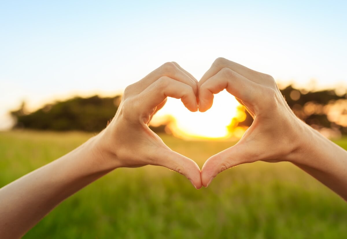 hands held in heart at sunset