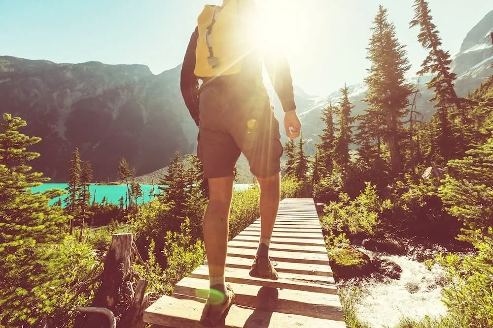 man walking sunny mountain path