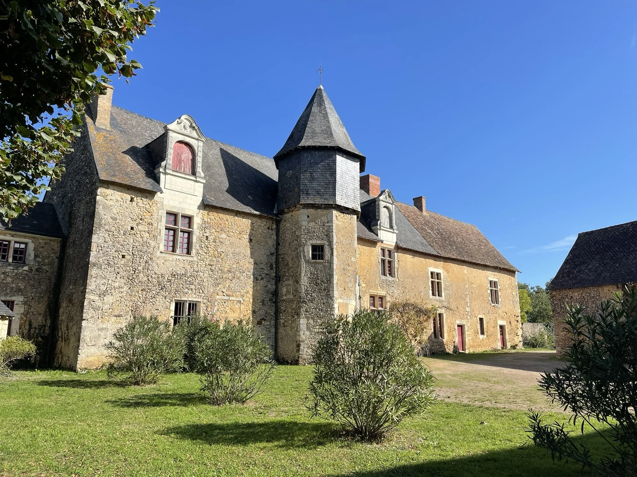 Intérieur d'une ancienne ferme en pierre avec un toit en bois, murs en pierre et petites fenêtres.