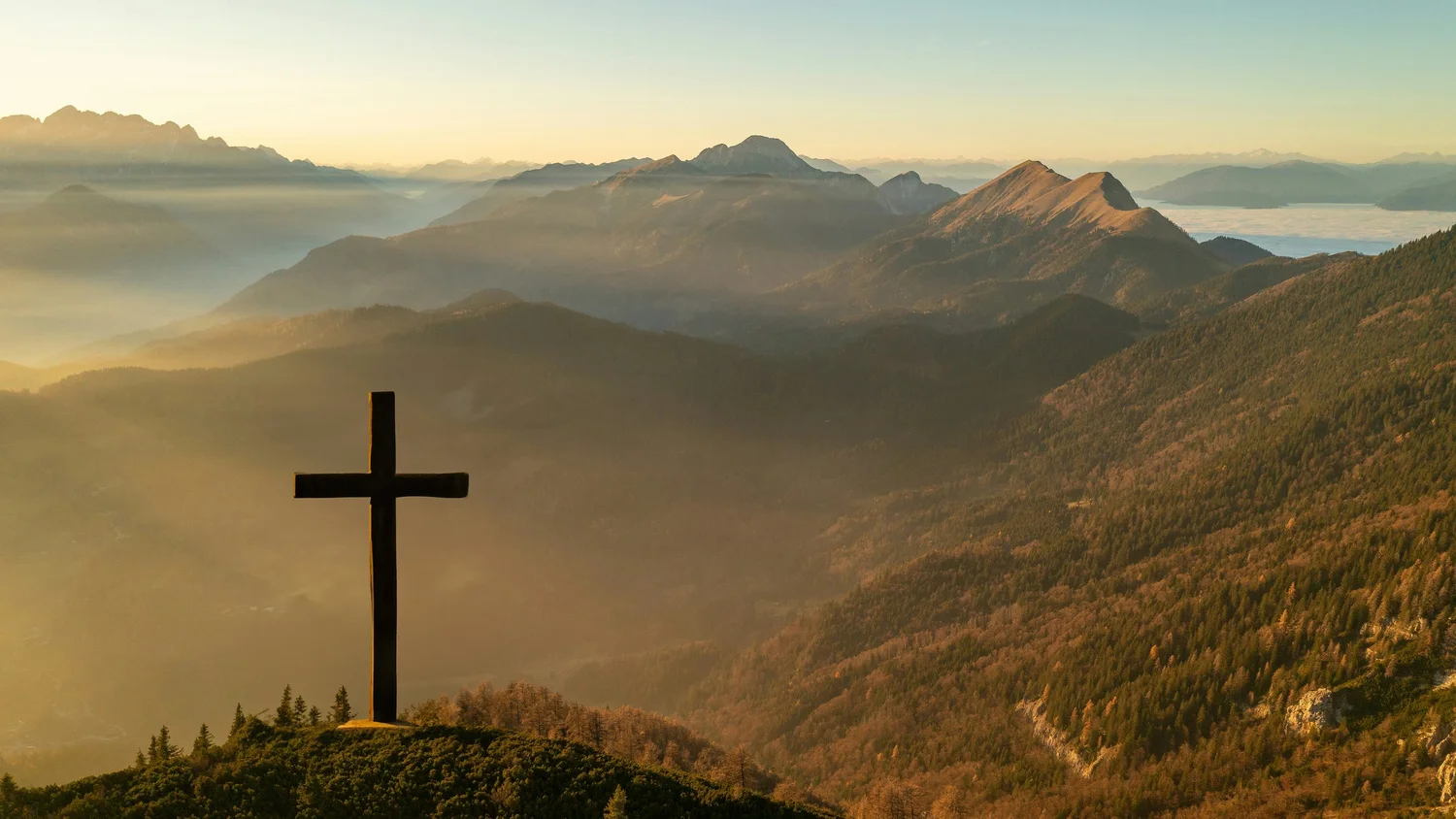 A cross on a mountaintop at sunrise