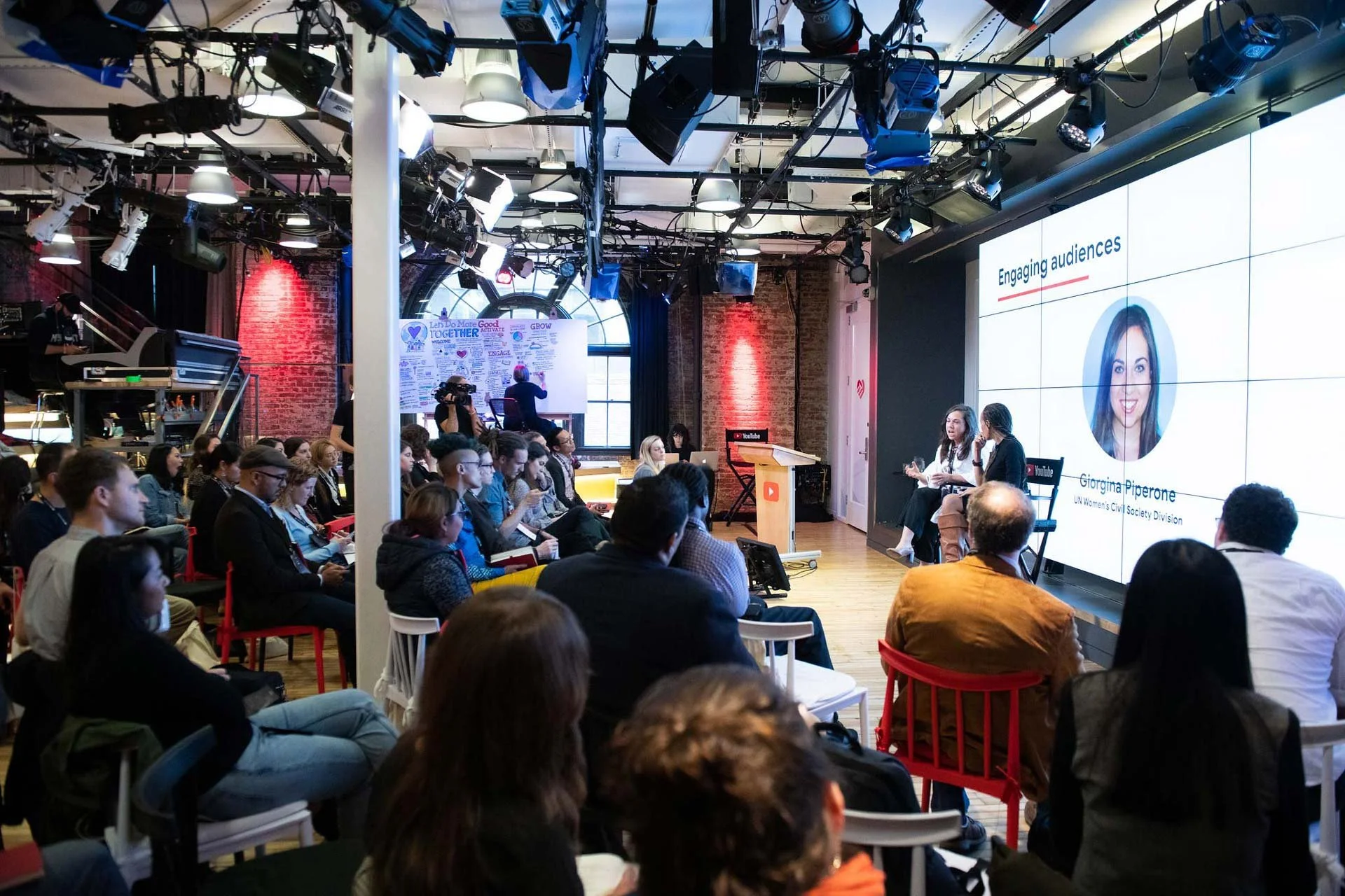 Woman onstage at Youtube HQ, addressing creators at a conference. 