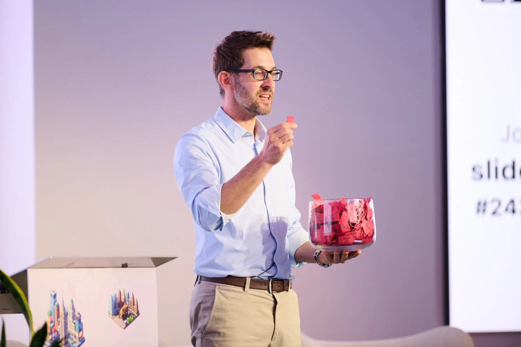 A man on stage holding up a raffle ticket at Deeplearning.AI tech conference 