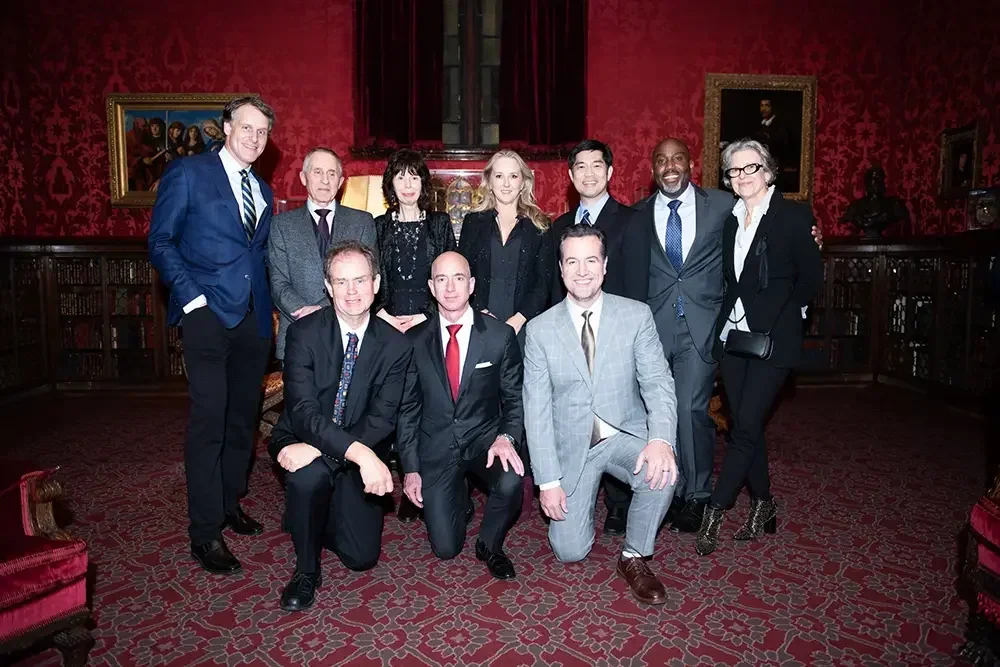A professional event photograph of Jeff Bezos, Simon Tolkien, and Oxford University staff at The Morgan Library