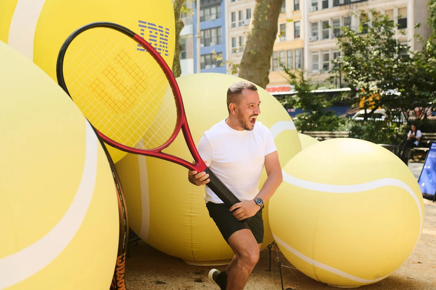 A man holding up a giant prop tennis racket at IBM's brand activation in Madison Square Park