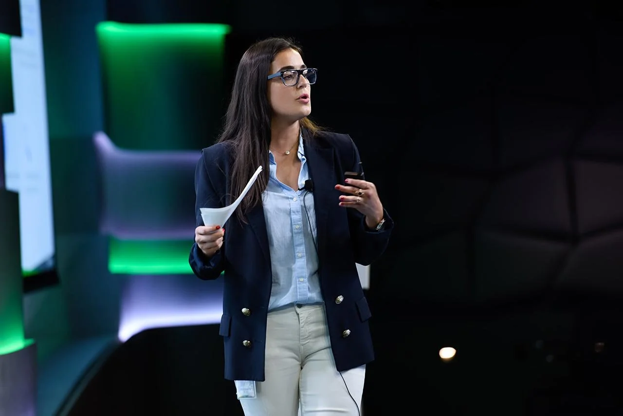 A woman onstage speaking at The Goblin King Room in Google HQ