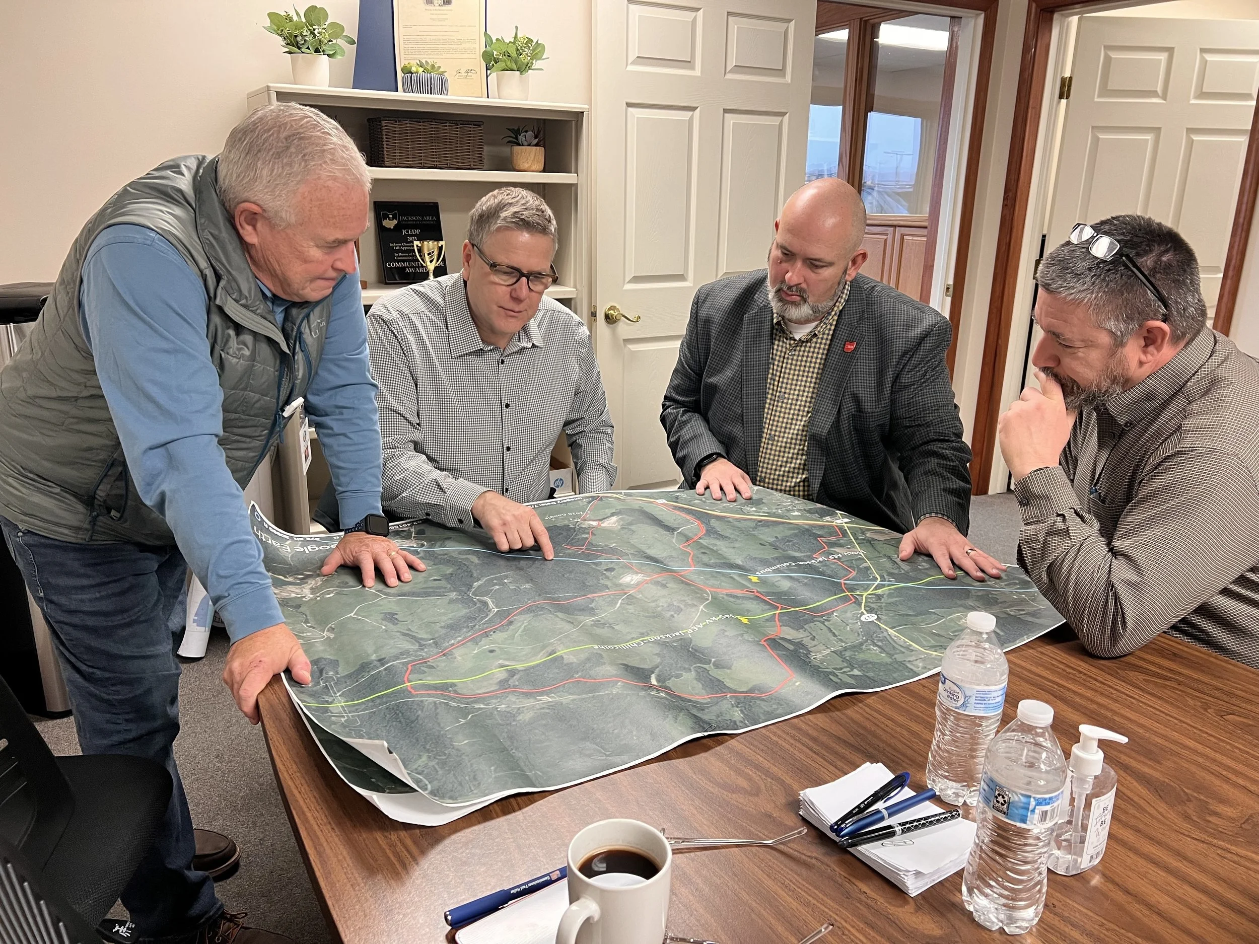 Larry Kid and three other men looking at a map on a table